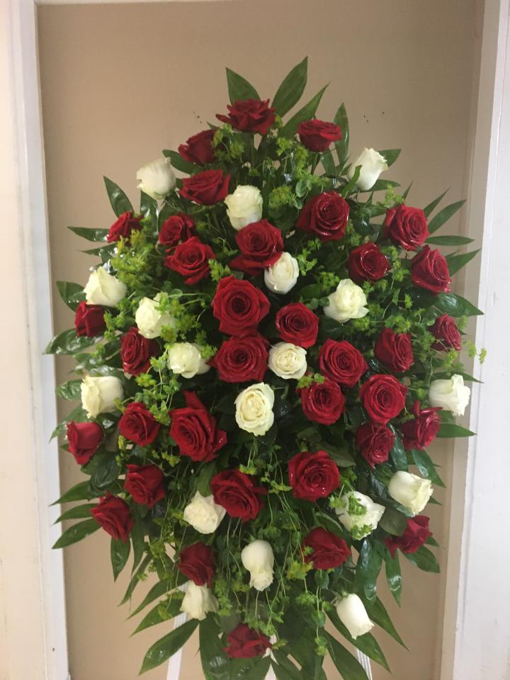 Standing spray of red and white roses with greenery
