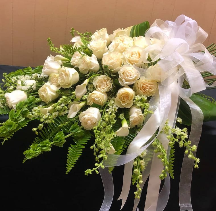Cream rose bouquet with white ribbon and trailing greenery