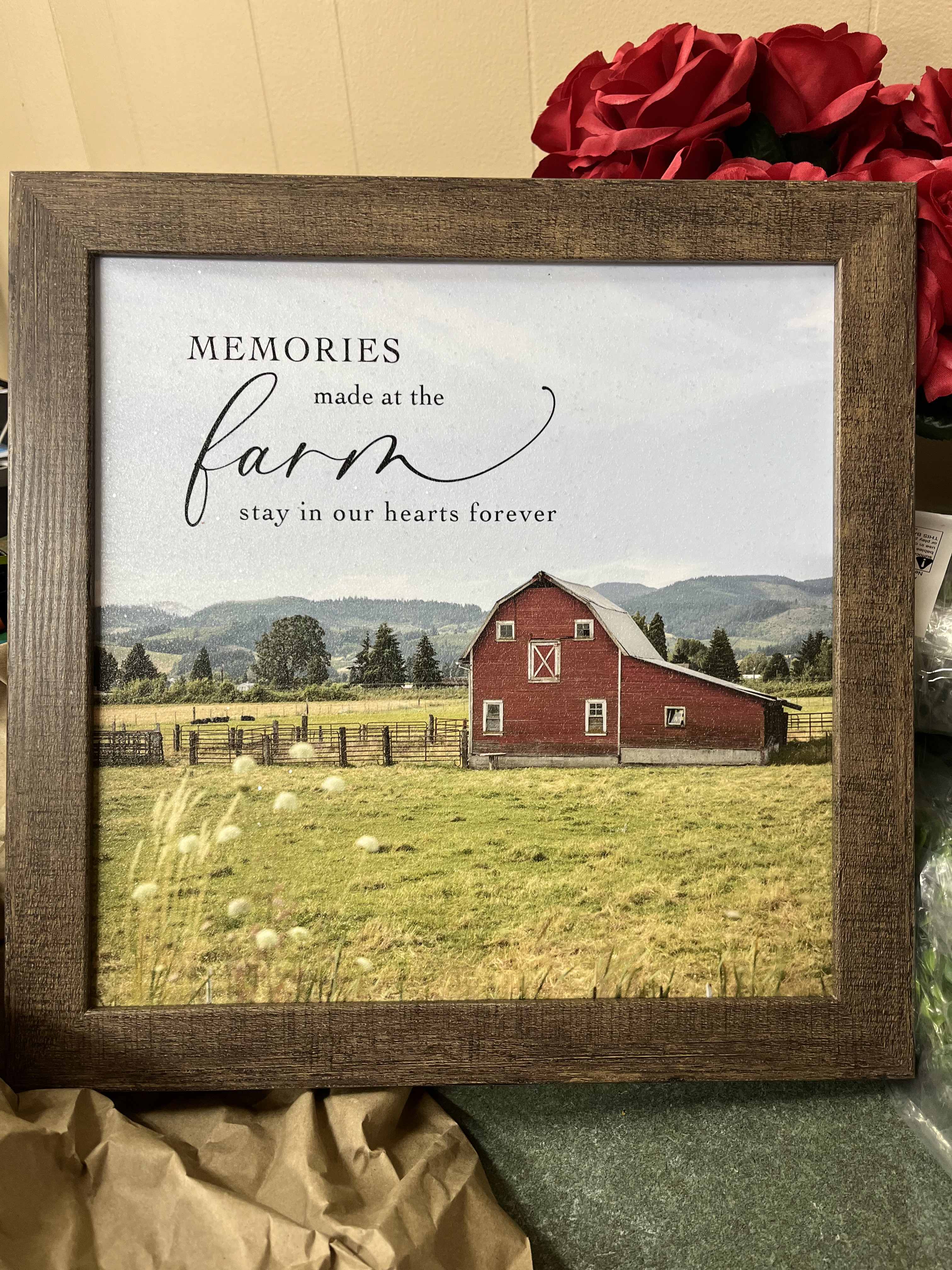 Framed farm sign with a red barn and red roses behind it