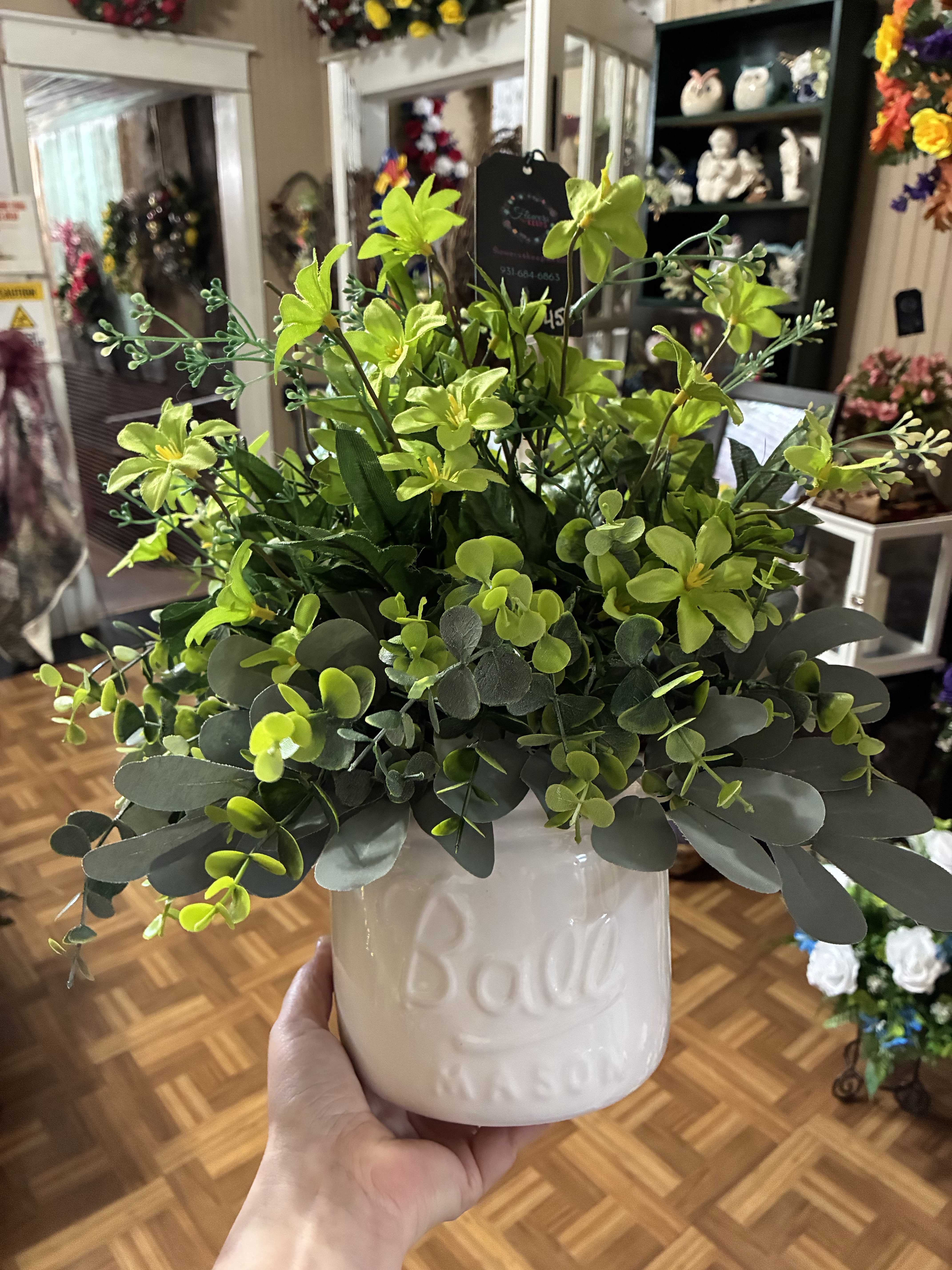 Green floral arrangement in a white ceramic pot
