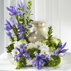 Purple irises and white daisies arranged around a gold urn candle.