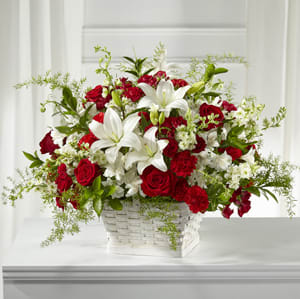 Red roses and white lilies arranged in a white basket