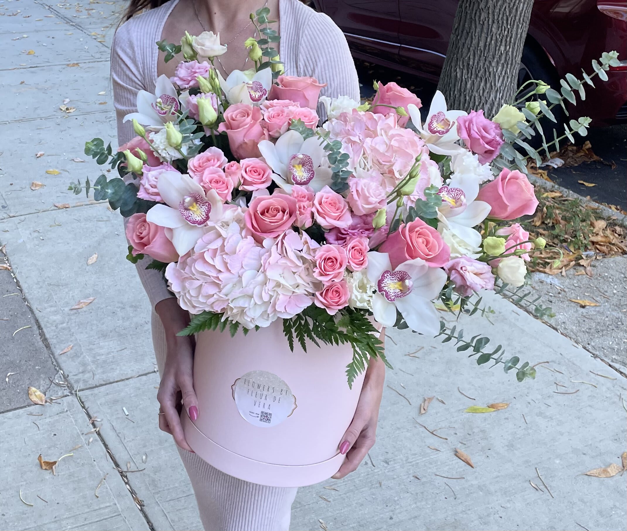 Pink roses and white orchids in a round pink box