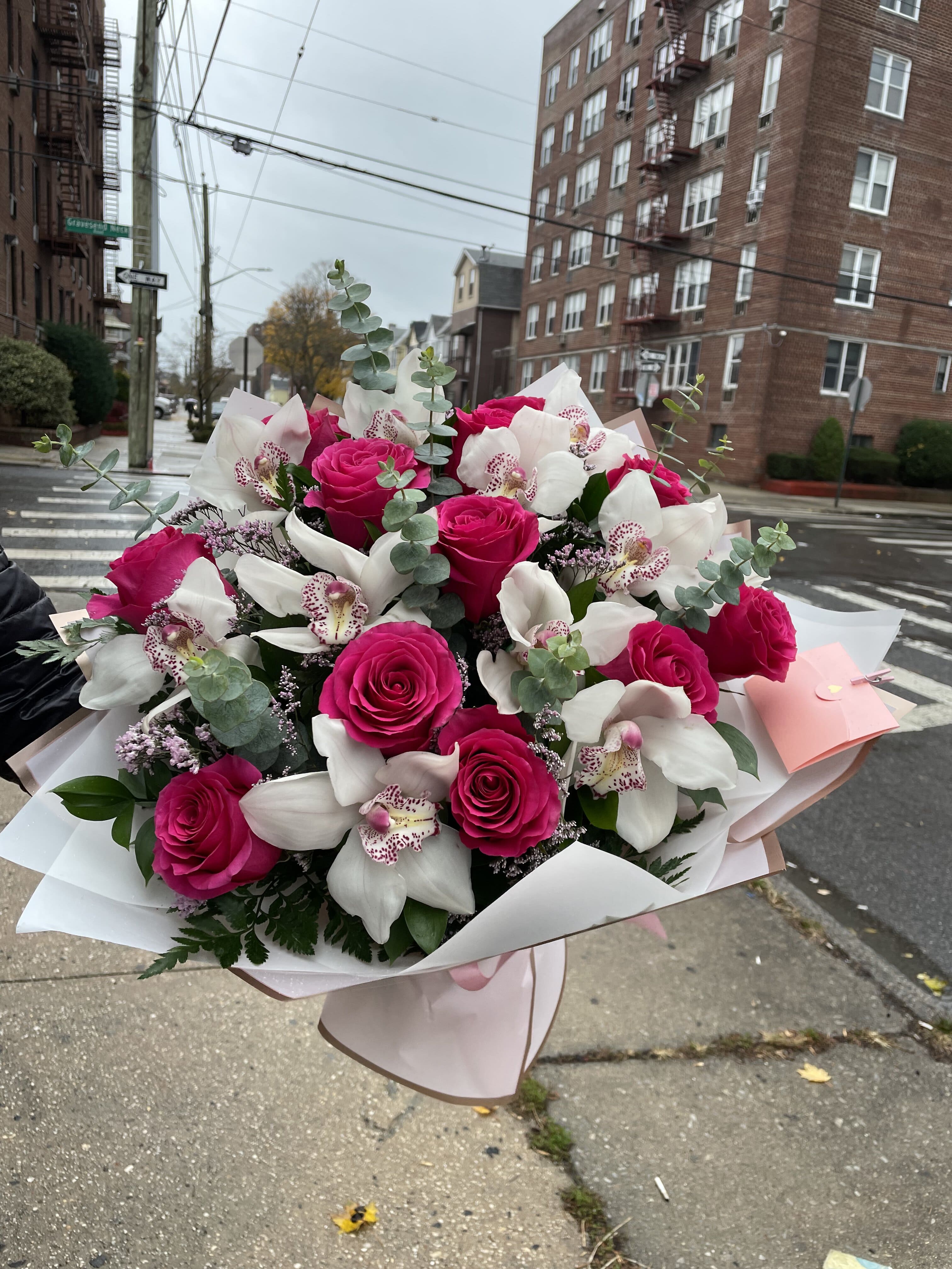 Bouquet of hot pink roses and white orchids wrapped in pale paper