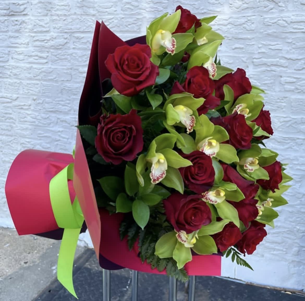 Bouquet of red roses and green orchids wrapped in pink paper