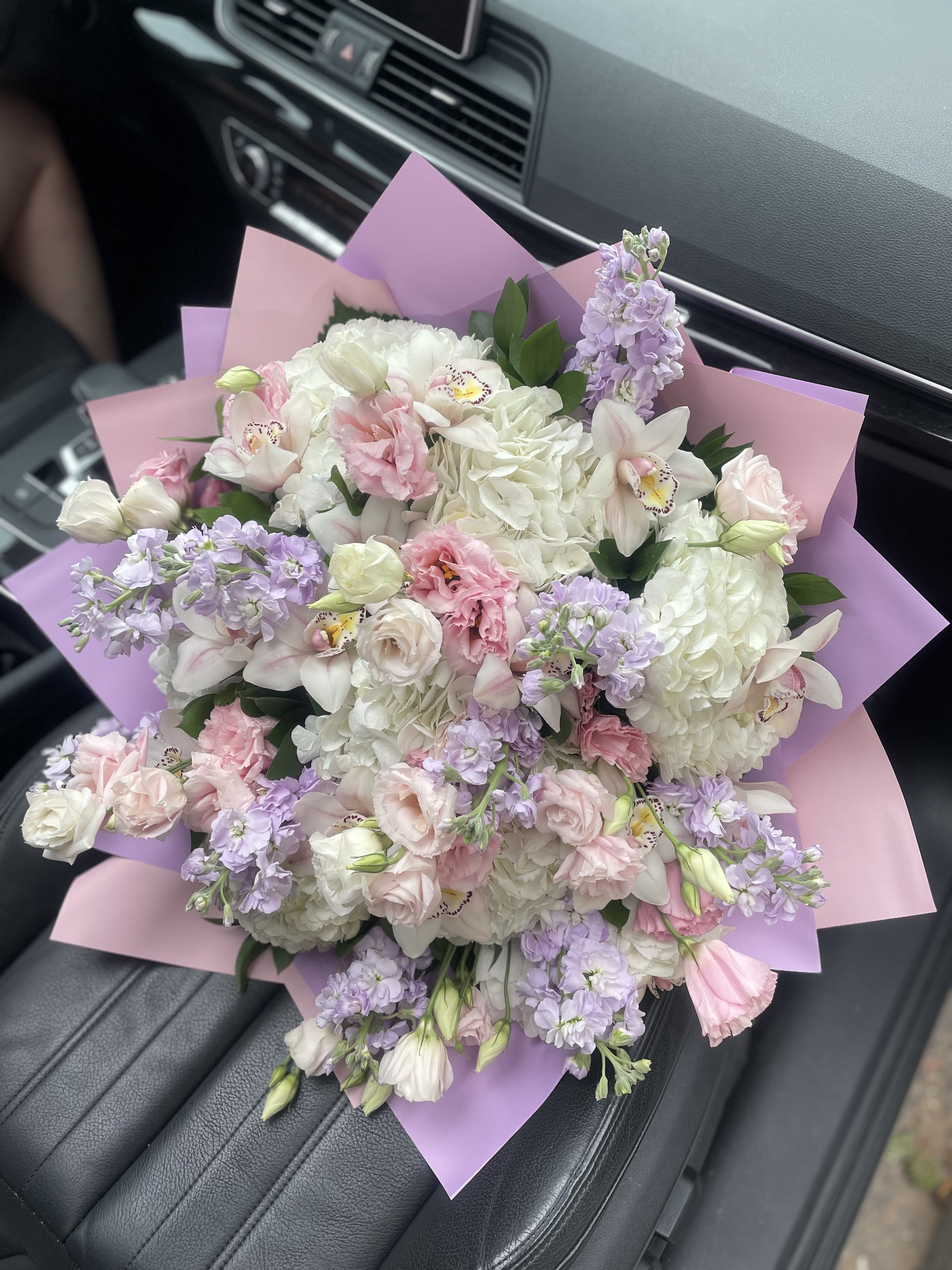 Bouquet of white and pale pink flowers wrapped in pink and lavender paper