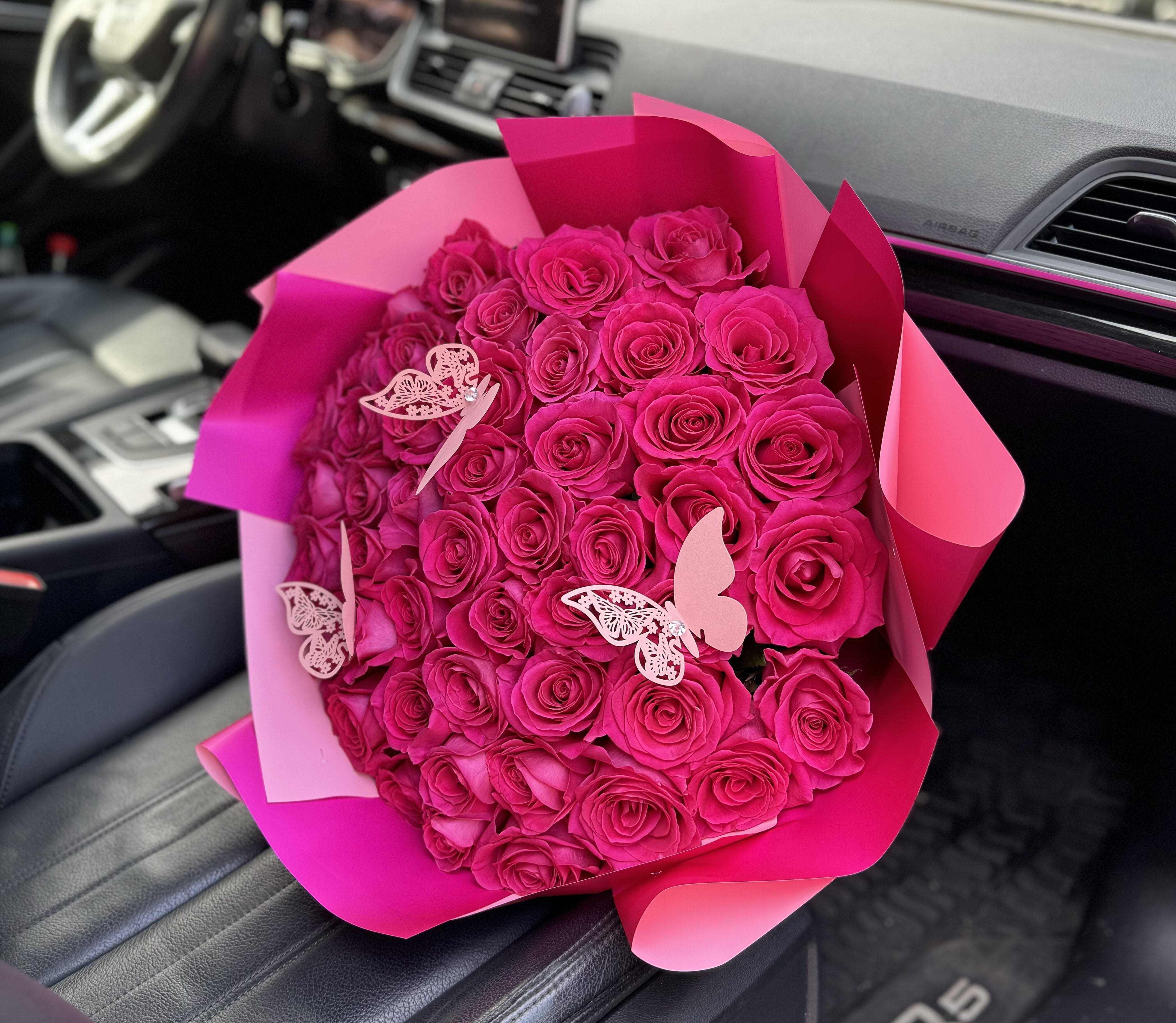 Bouquet of hot pink roses wrapped in pink paper with butterfly decorations