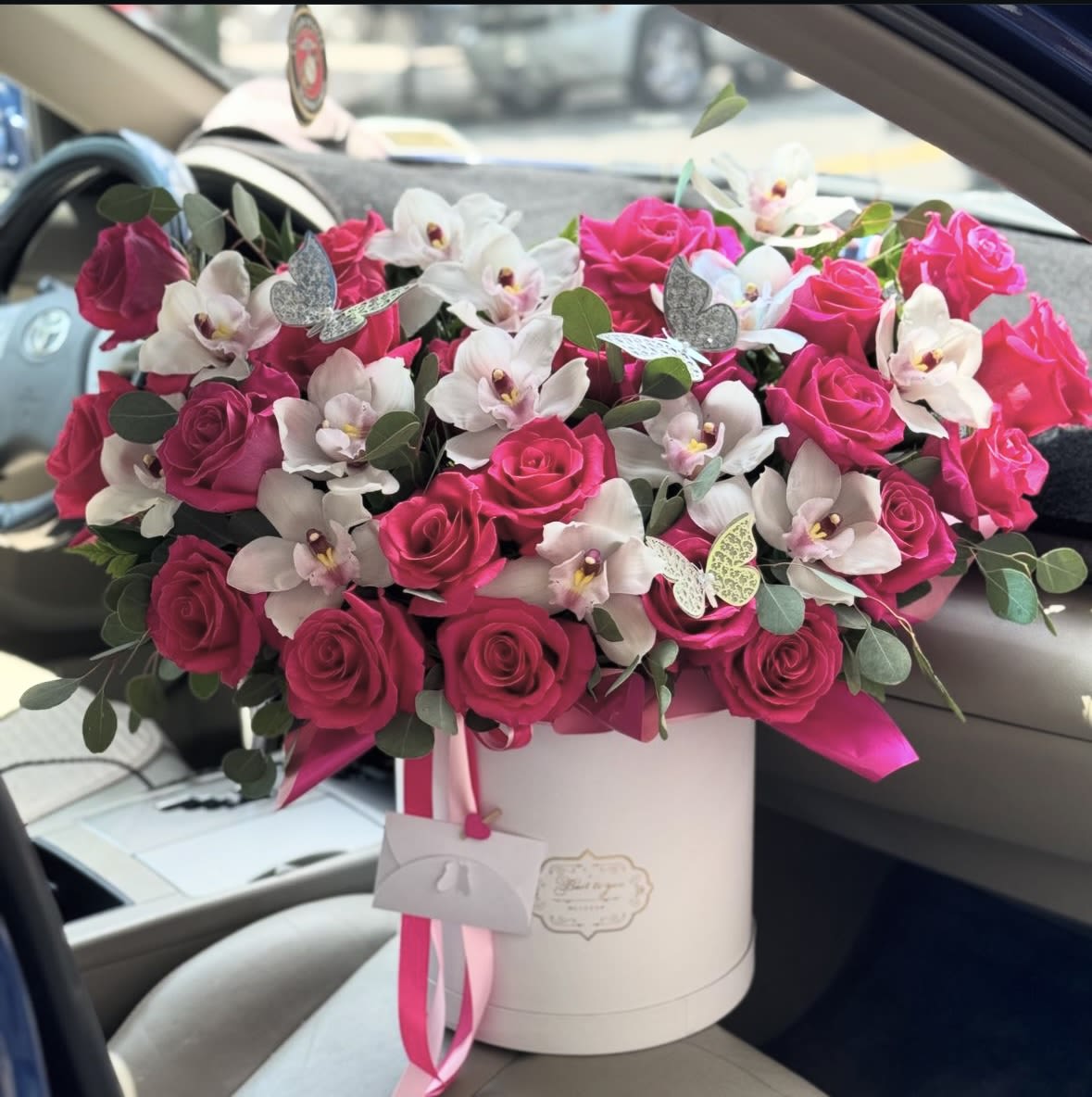Pink roses and white orchids in a white hatbox with ribbon