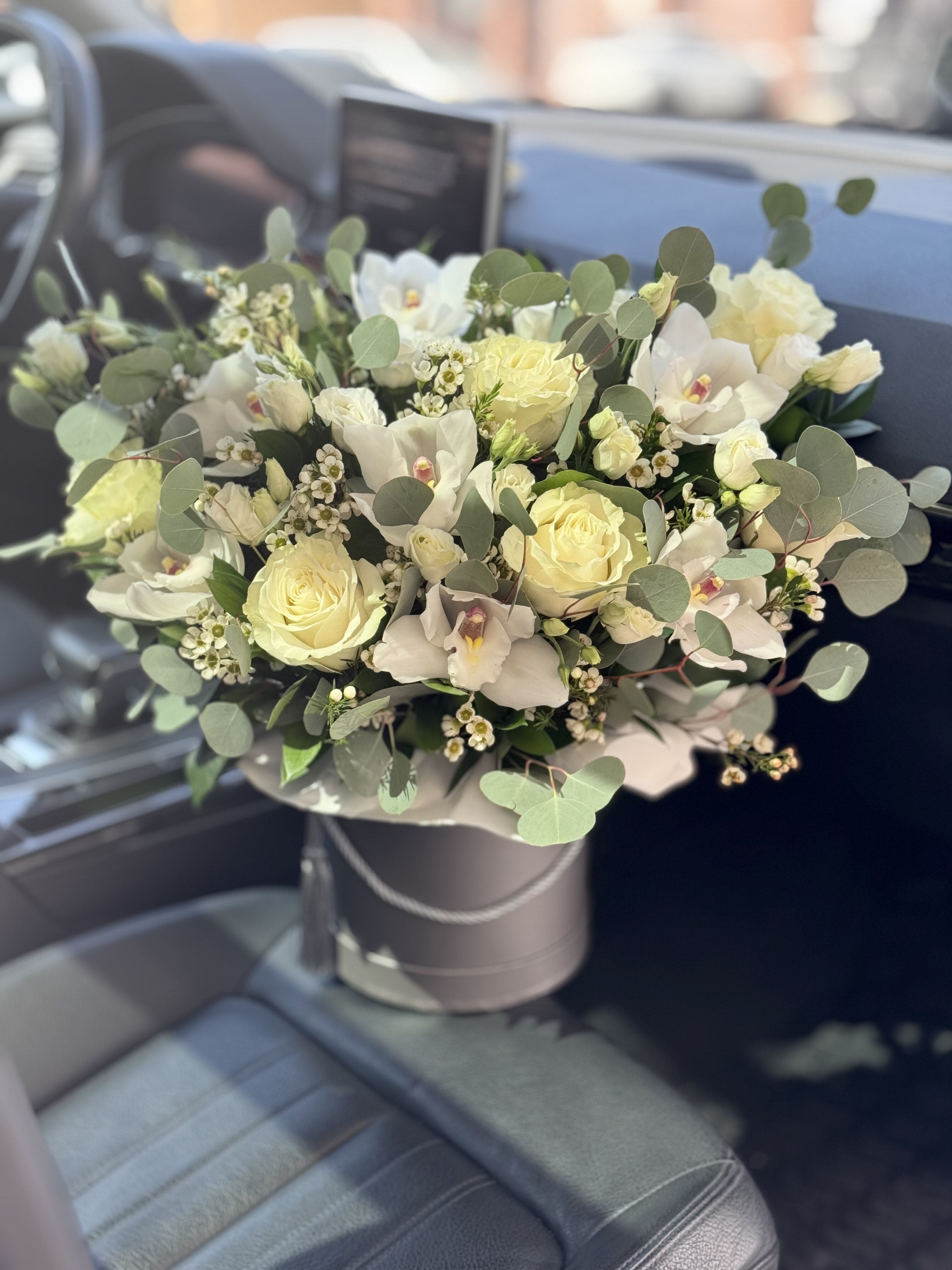 White rose and orchid bouquet in a round box