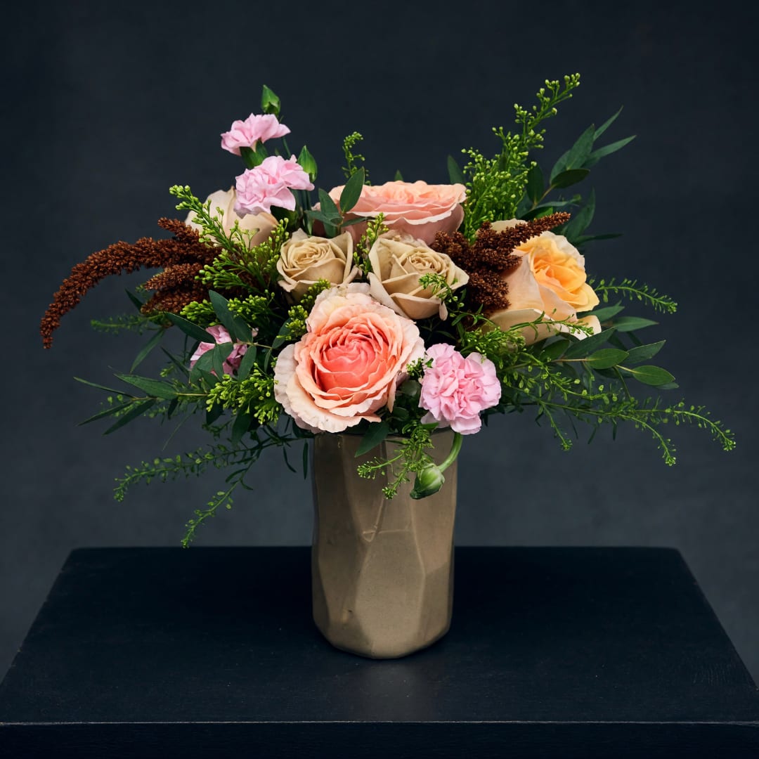 Pink and peach roses arranged in a tall vase