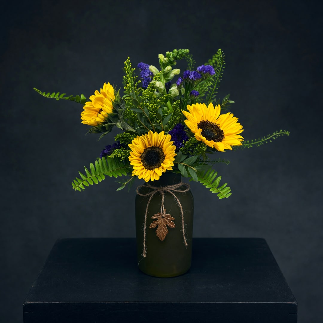 Sunflower arrangement in a dark vase with purple accents