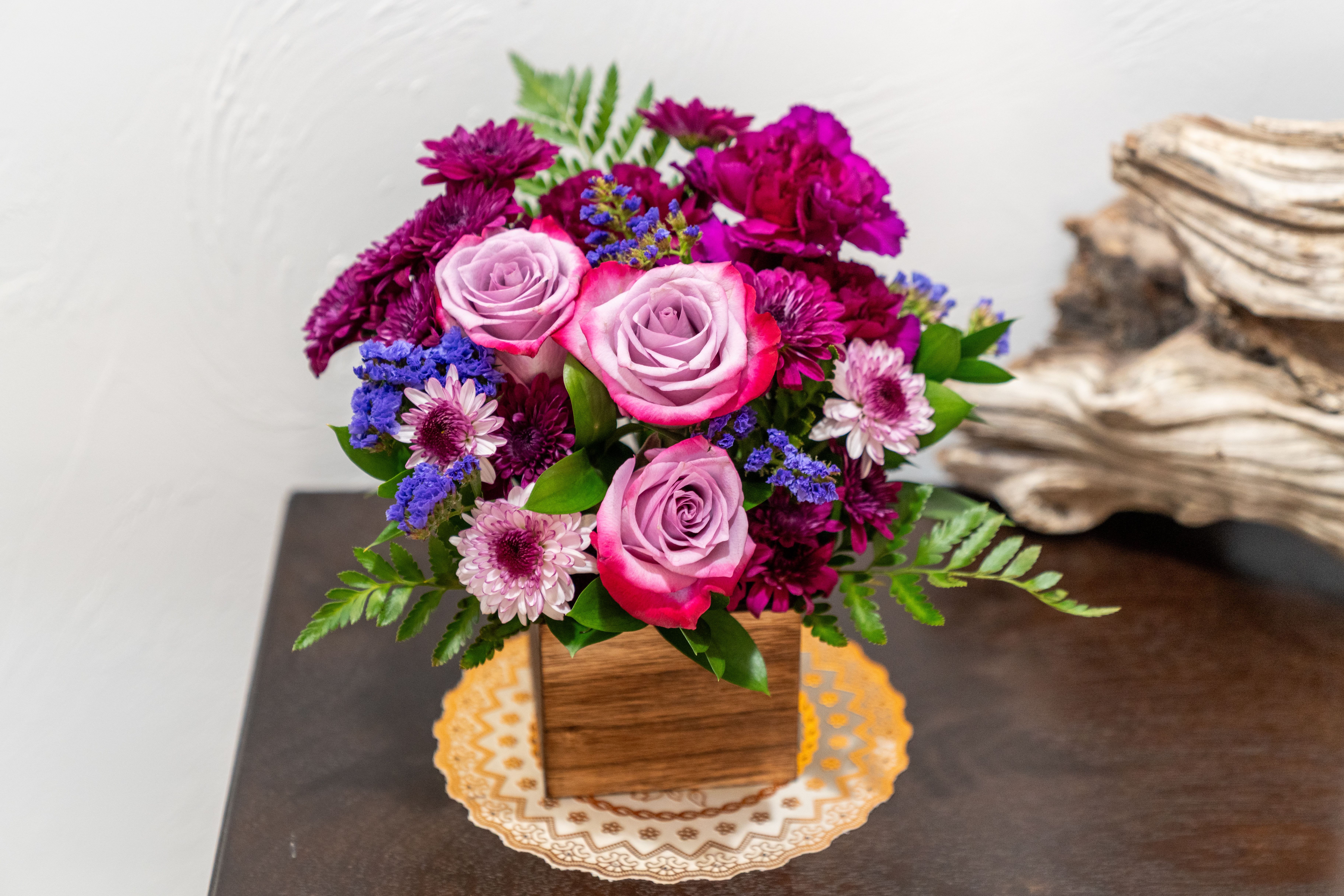 Pink roses and purple flowers arranged in a wooden box