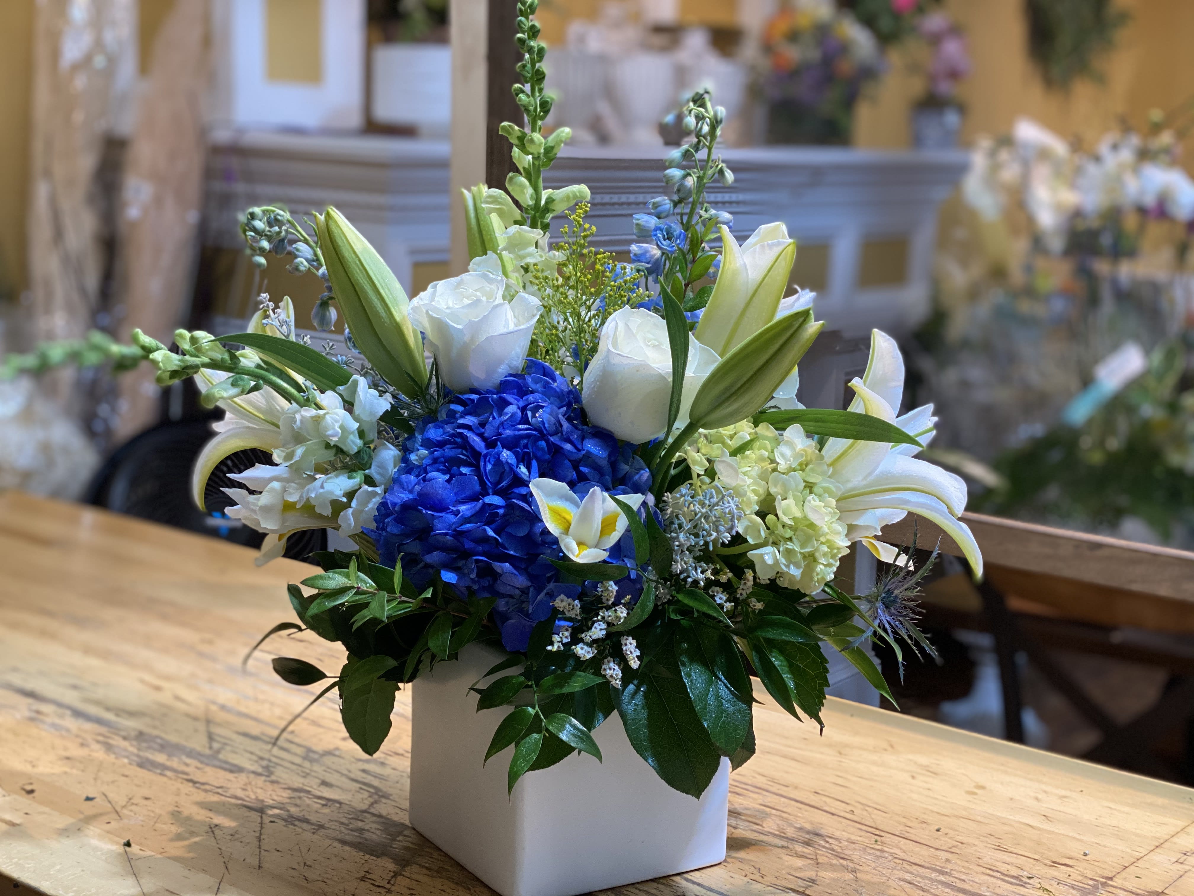 Blue hydrangea and white lilies in a white square vase