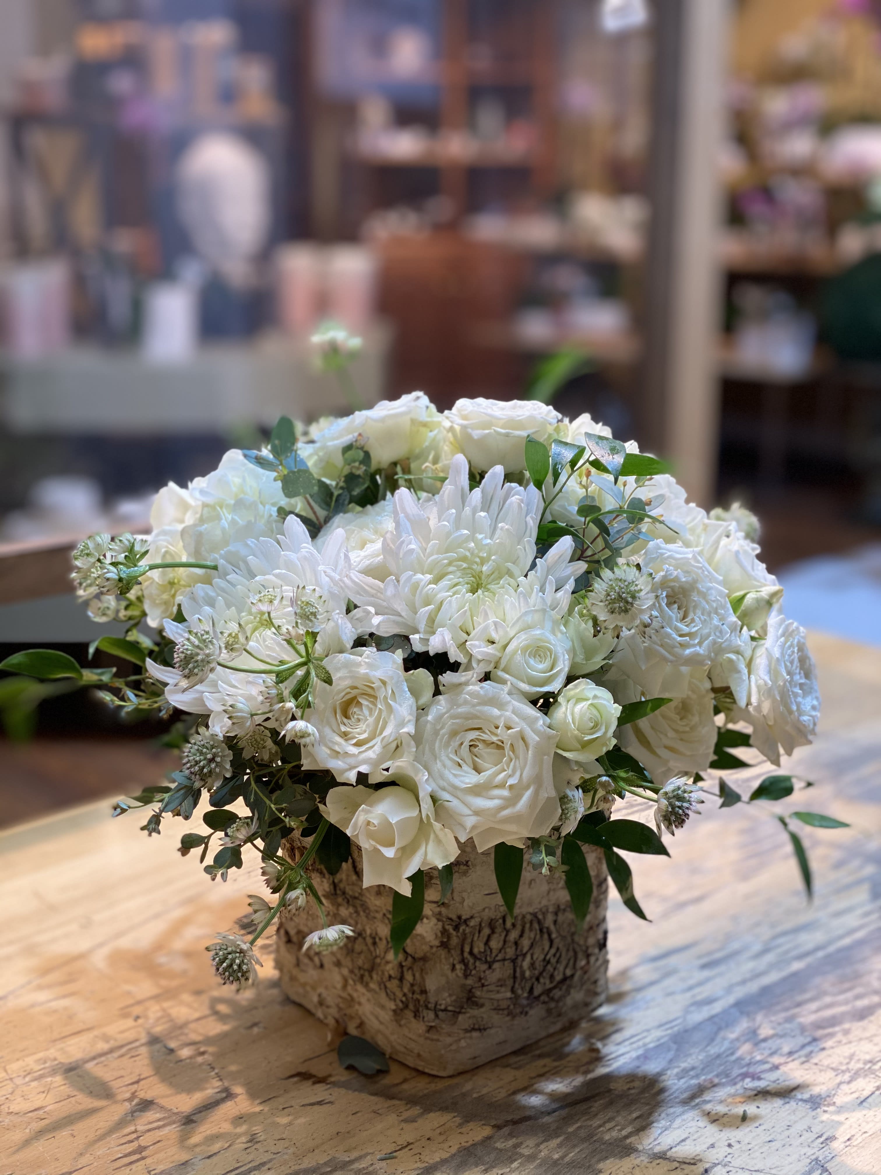 White roses and chrysanthemums arranged in a bark-covered container