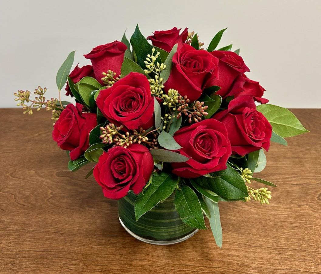 Red roses arranged in a green glass vase