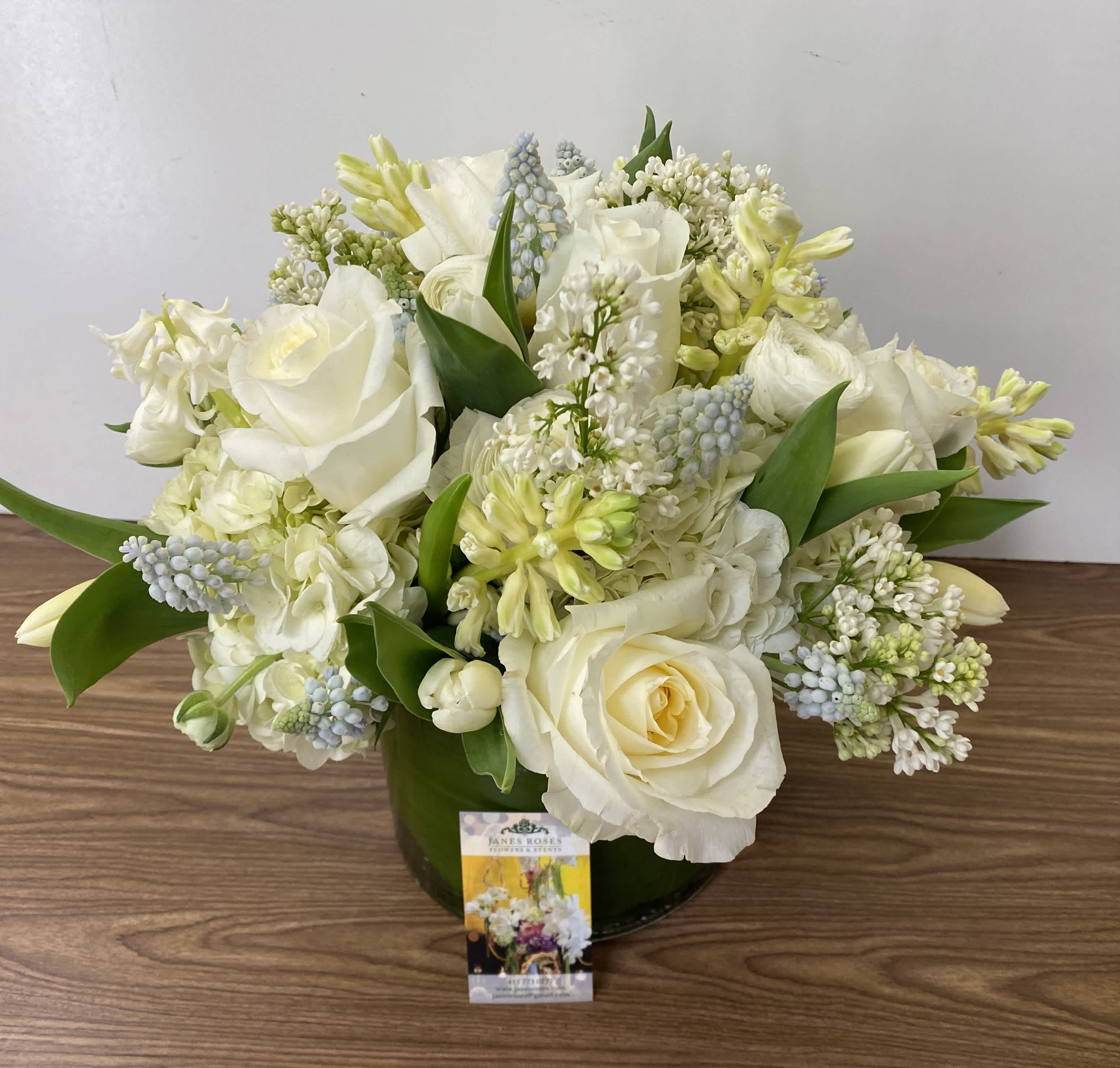 White rose and mixed white flower arrangement in a green vase