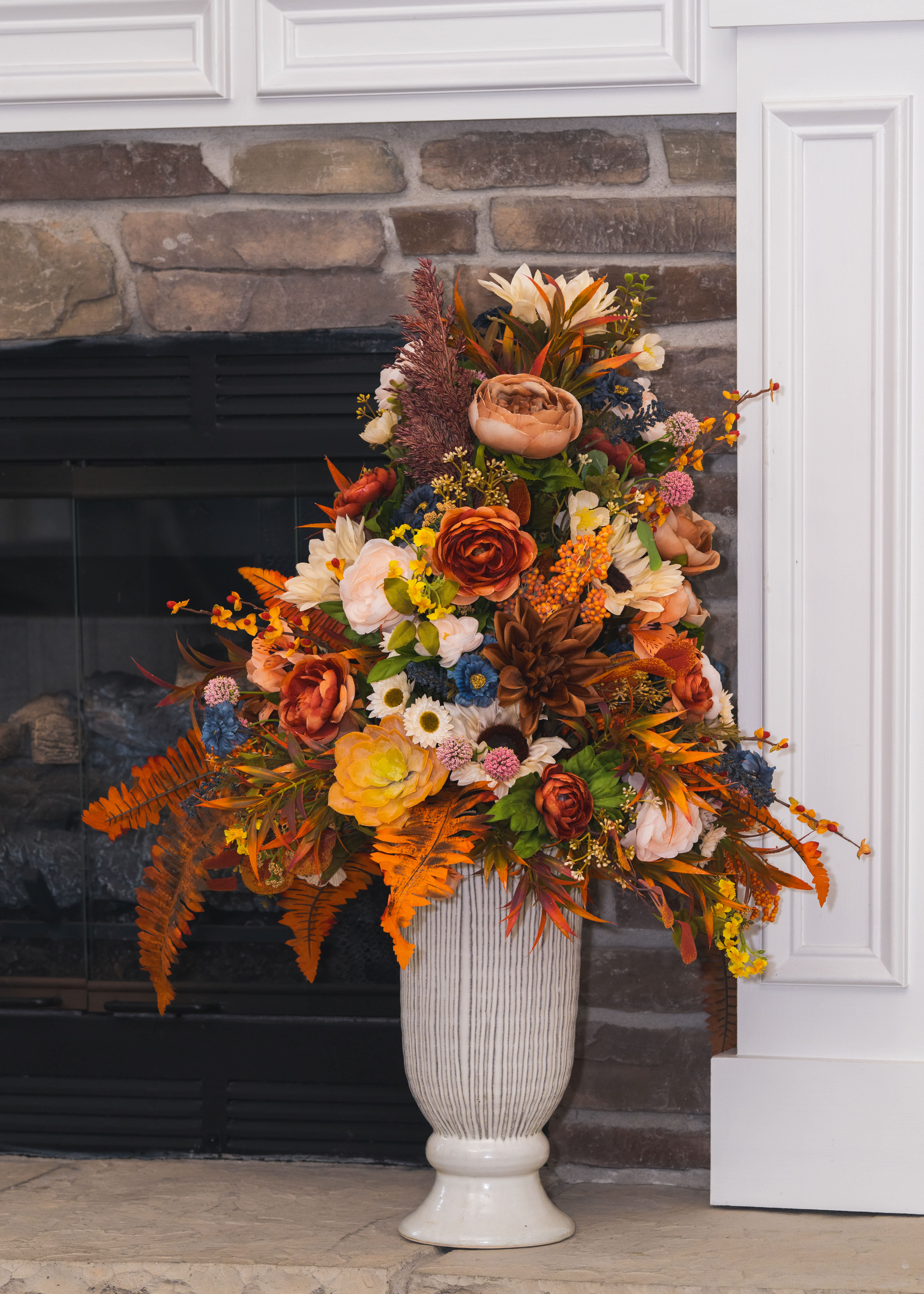 Tall autumn floral arrangement in a white pedestal vase