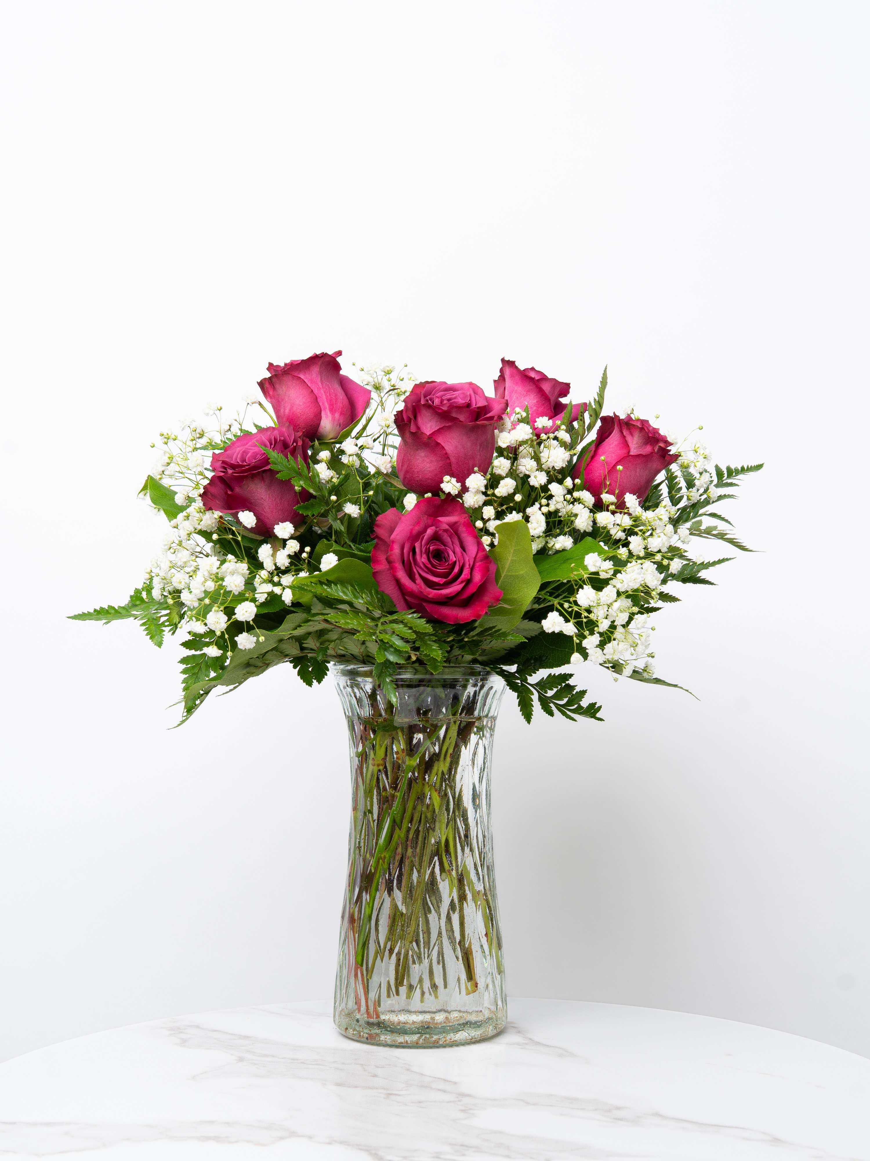 Pink roses arranged in a clear glass vase with white filler flowers