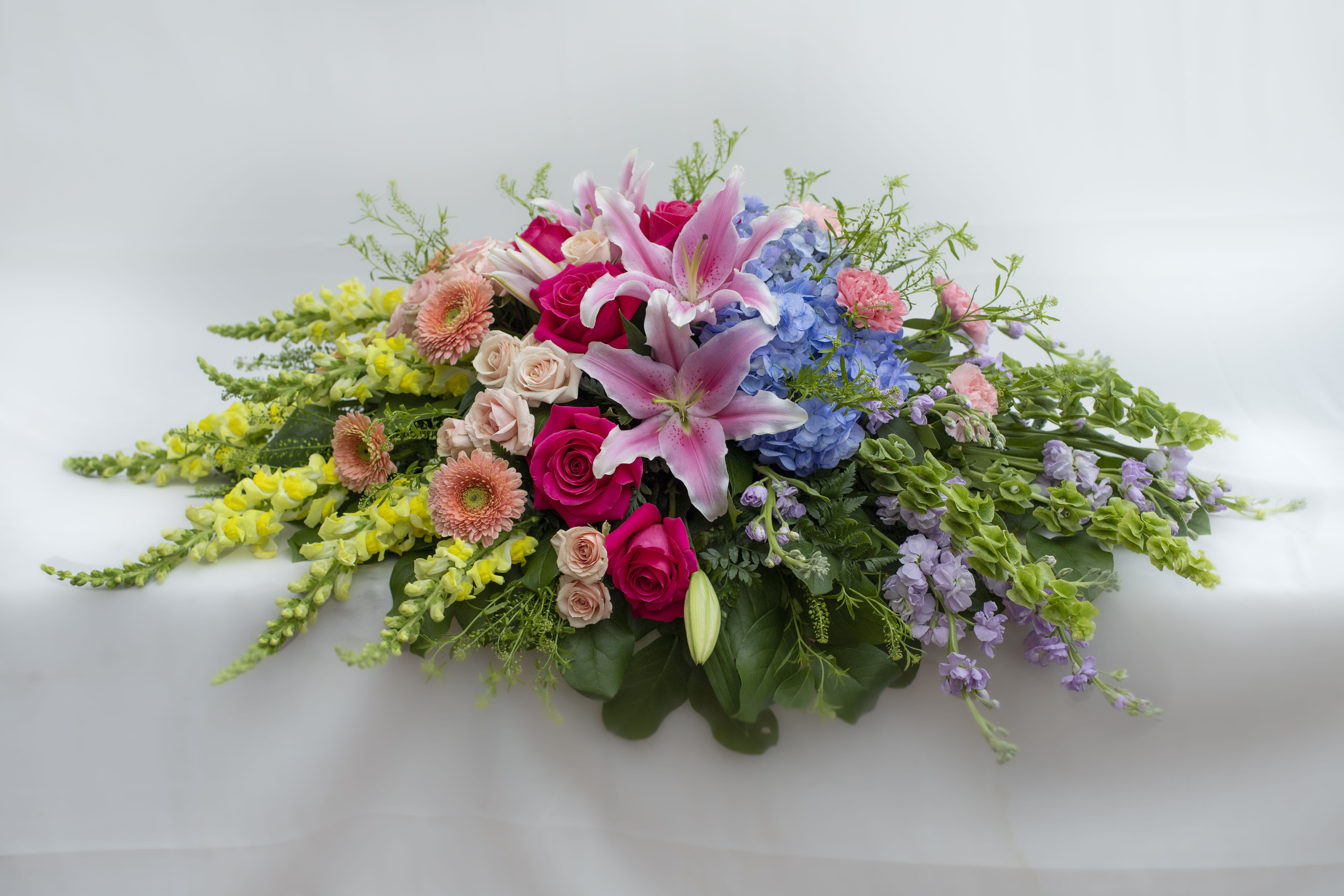 Low floral spray with pink lilies, roses, hydrangeas, and yellow blooms