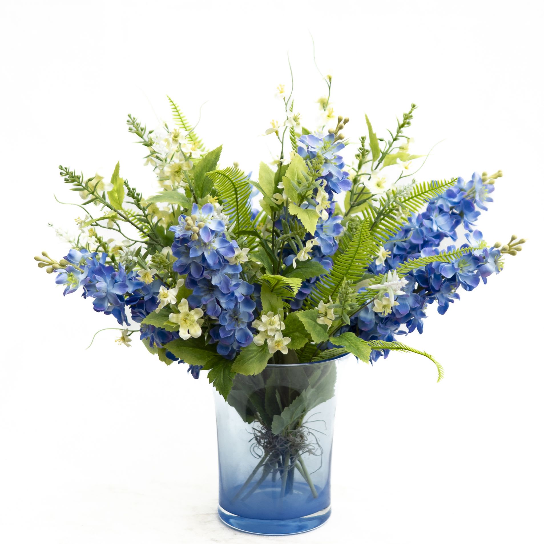 Blue hydrangea-like flowers in a glass vase with white filler blooms