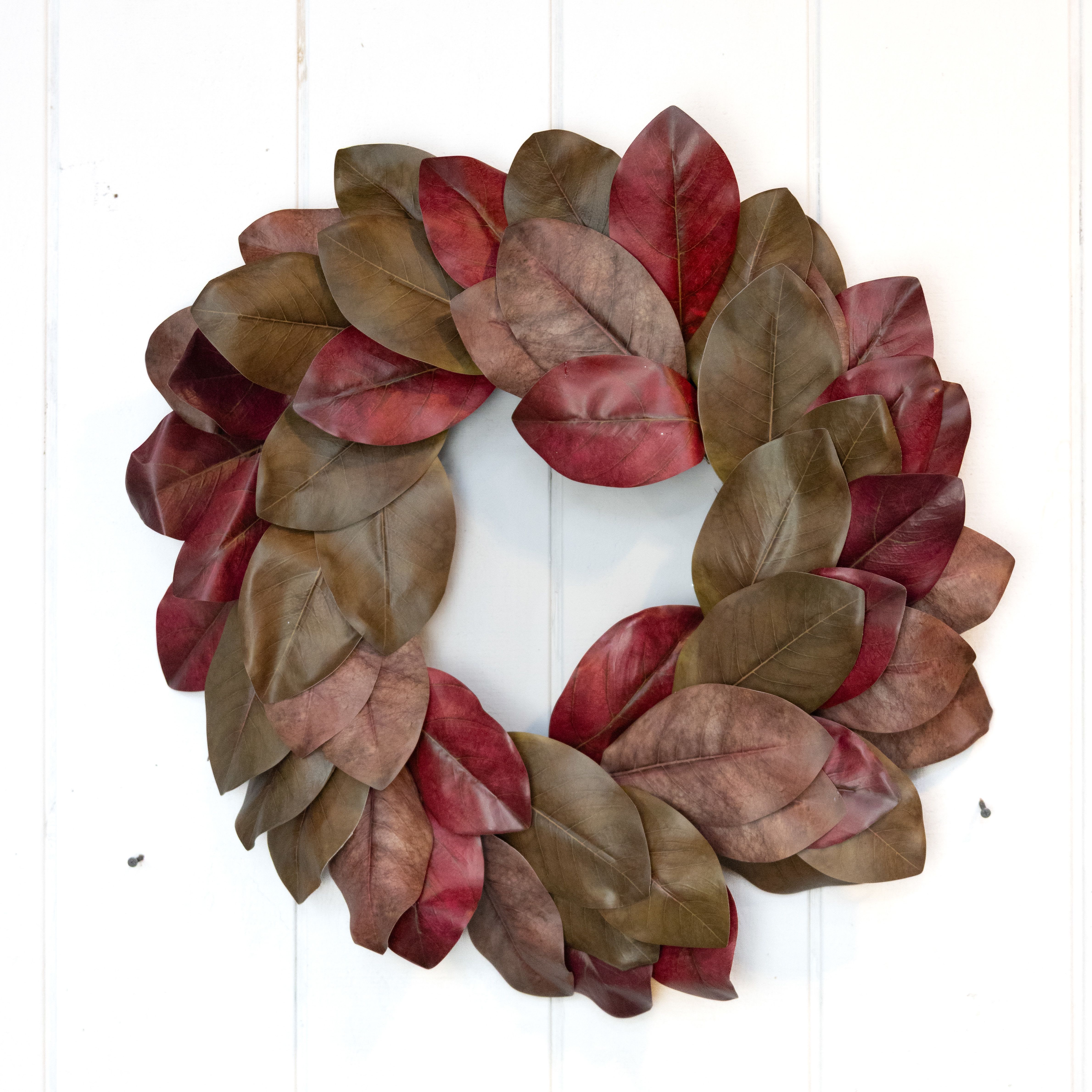 Leaf wreath in red, burgundy, and brown tones on a white door