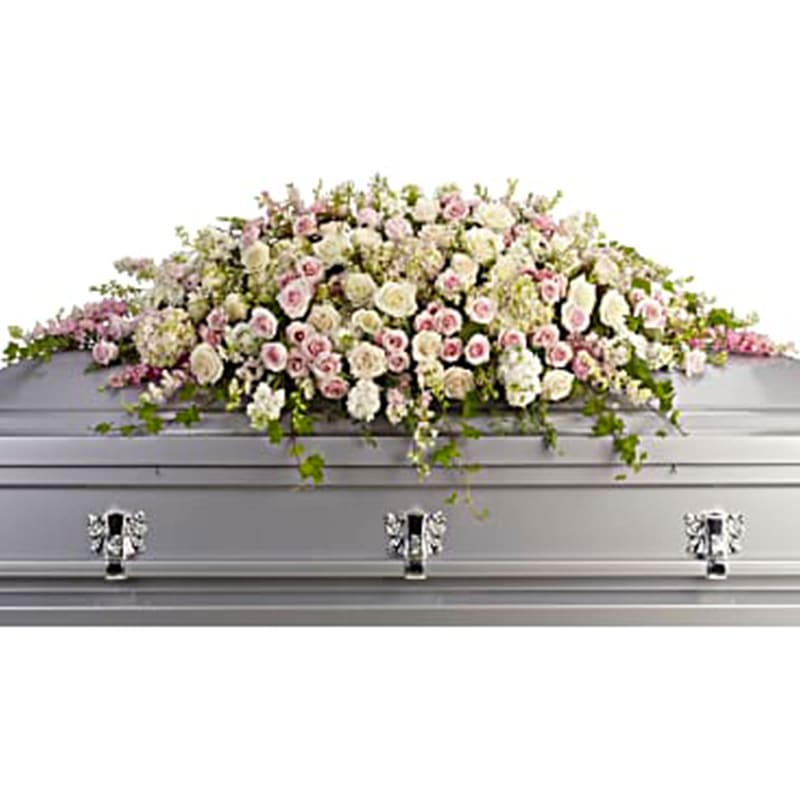 White and pink floral casket spray on a silver casket