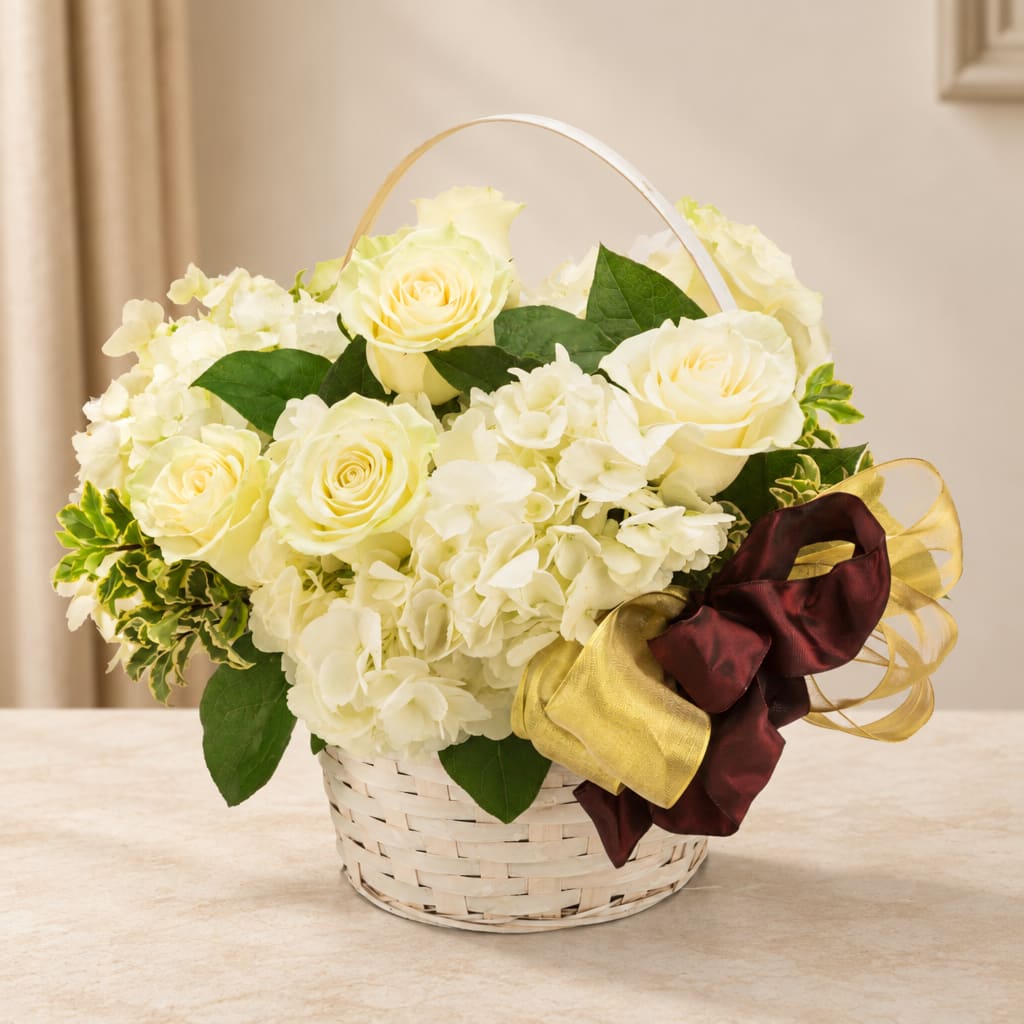 Cream roses and white hydrangeas in a white basket with ribbon