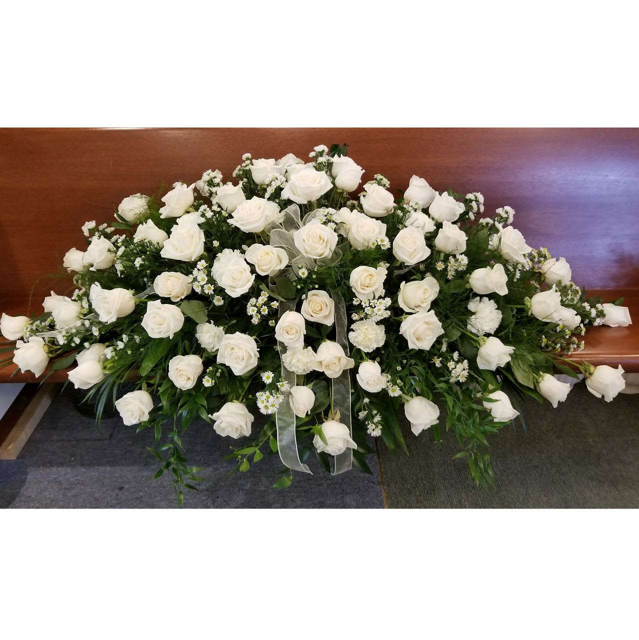Large white rose arrangement on a wooden casket