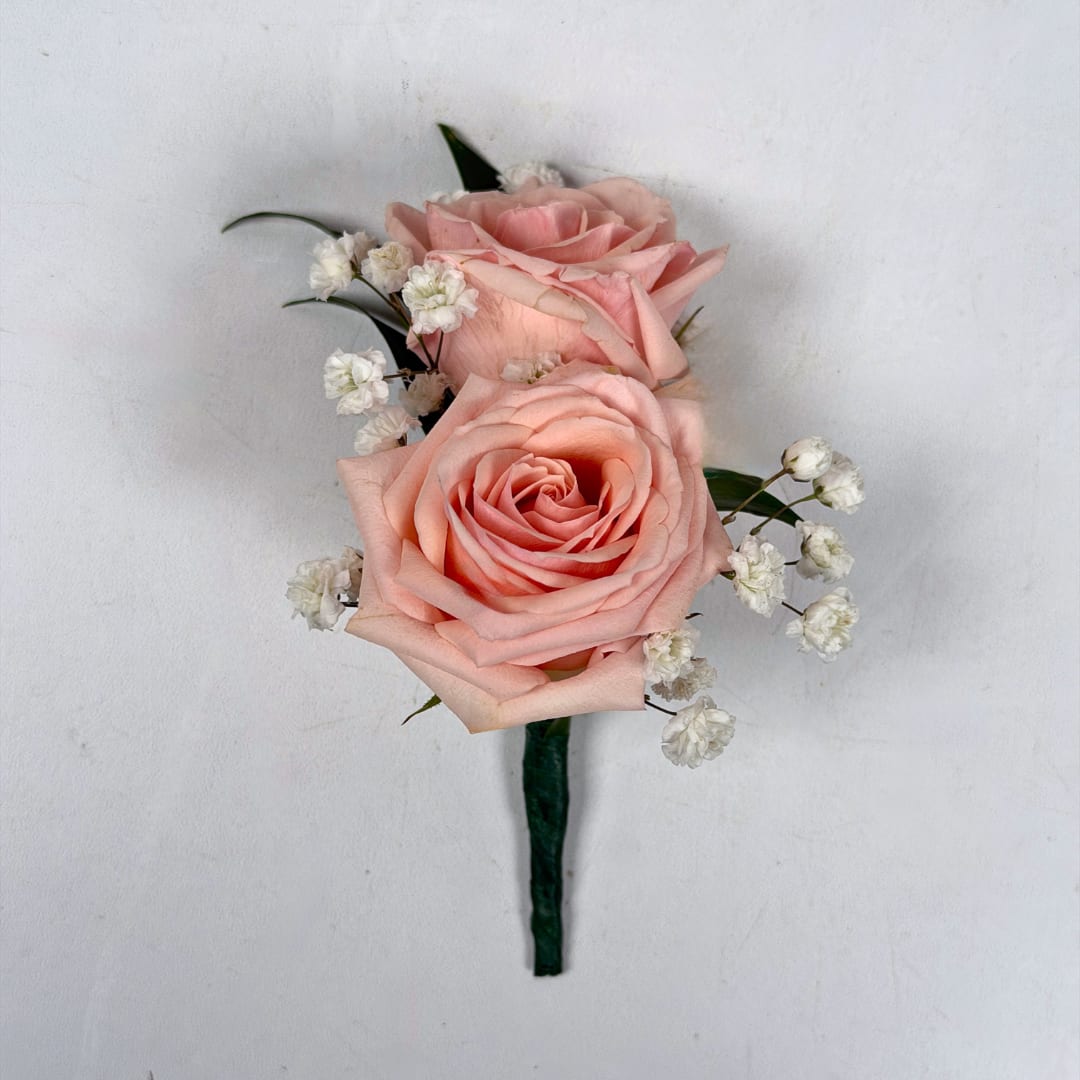 Rose Quartz Boutonniere - Two pale blush roses sit snugly together in this Rose Quartz boutonniere, perfectly made for prom night. The soft pink and white palette reads romantic and refined, and the foliage gives depth and contrast to the lighter colored blooms.  The standard design is hand-wrapped with dark green stem wrap and a boutonniere pin is included so it sits neatly on a suit or jacket. Upgrade to deluxe to have your boutonniere wrapped in the shimmering pink sheer ribbon pictured. Upgrading to premium includes this ribbon wrap, and also adds pink rhinestone sparkle accents as a dazzling extra touch to make your night even more special.  If you want to change the color of either the ribbon wrap or the sparkle accents, check out our add-ons below or at checkout and pick your desired color.