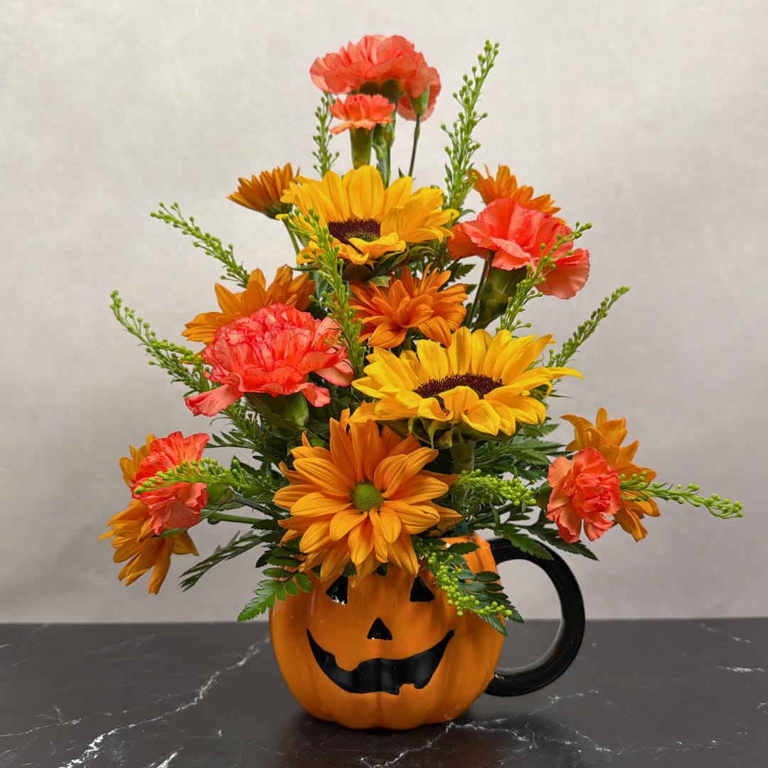 Orange and yellow flower arrangement in a jack-o'-lantern mug
