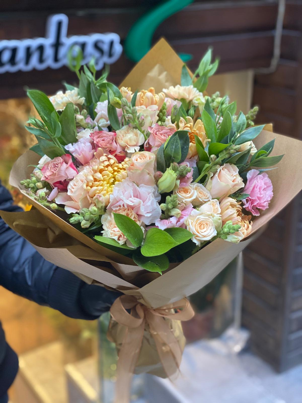 Bouquet of pink and peach flowers wrapped in brown paper