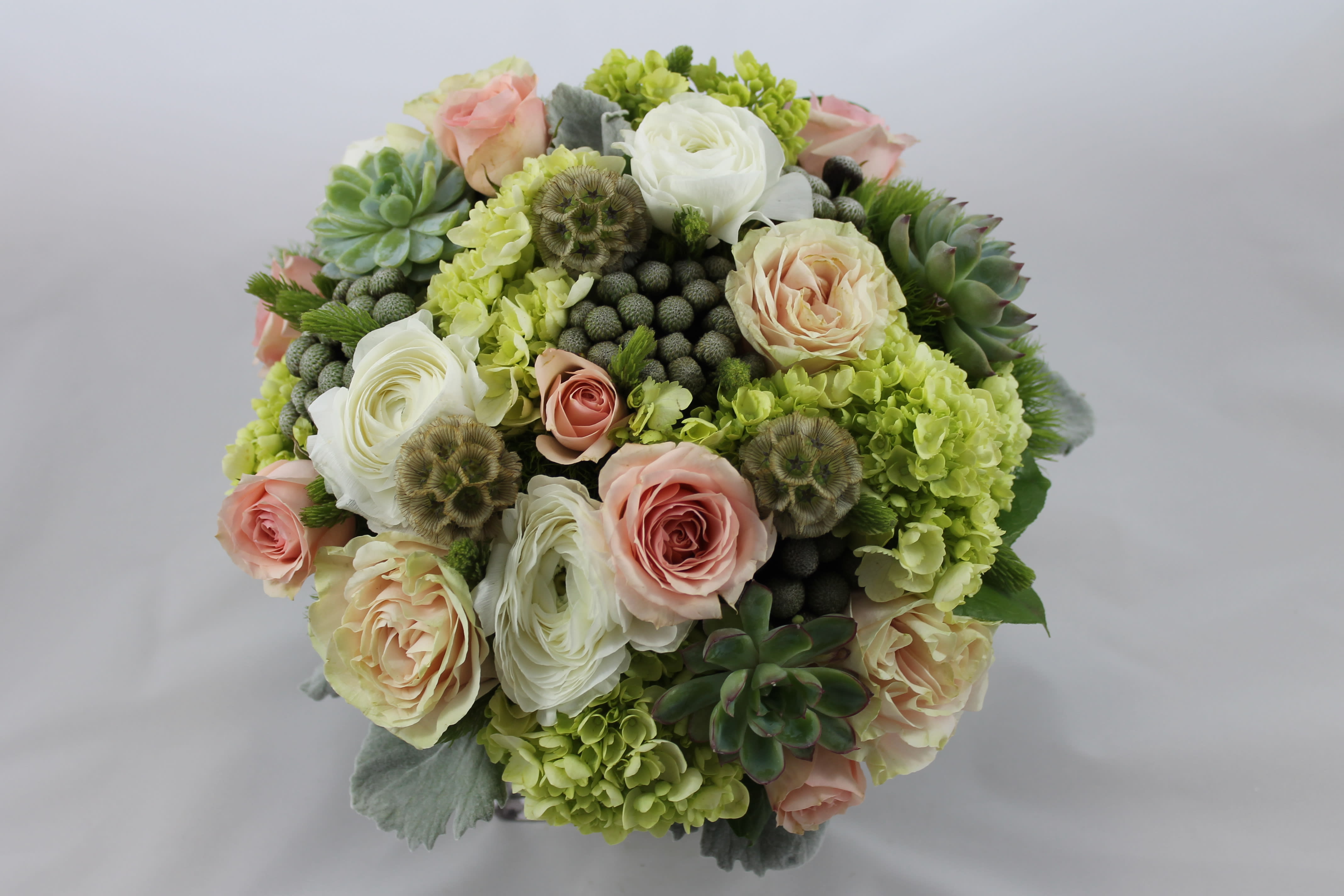 Round bouquet of pale roses, white blooms, and succulents