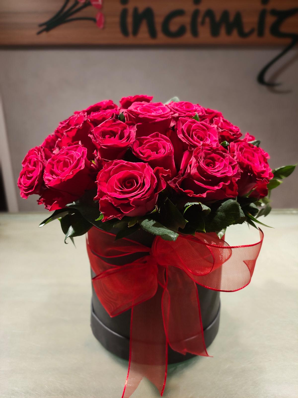 Red roses arranged in a black box with a sheer red ribbon