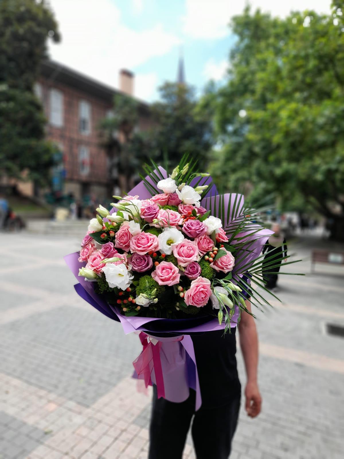 Large bouquet of pink and white roses with purple wrapping