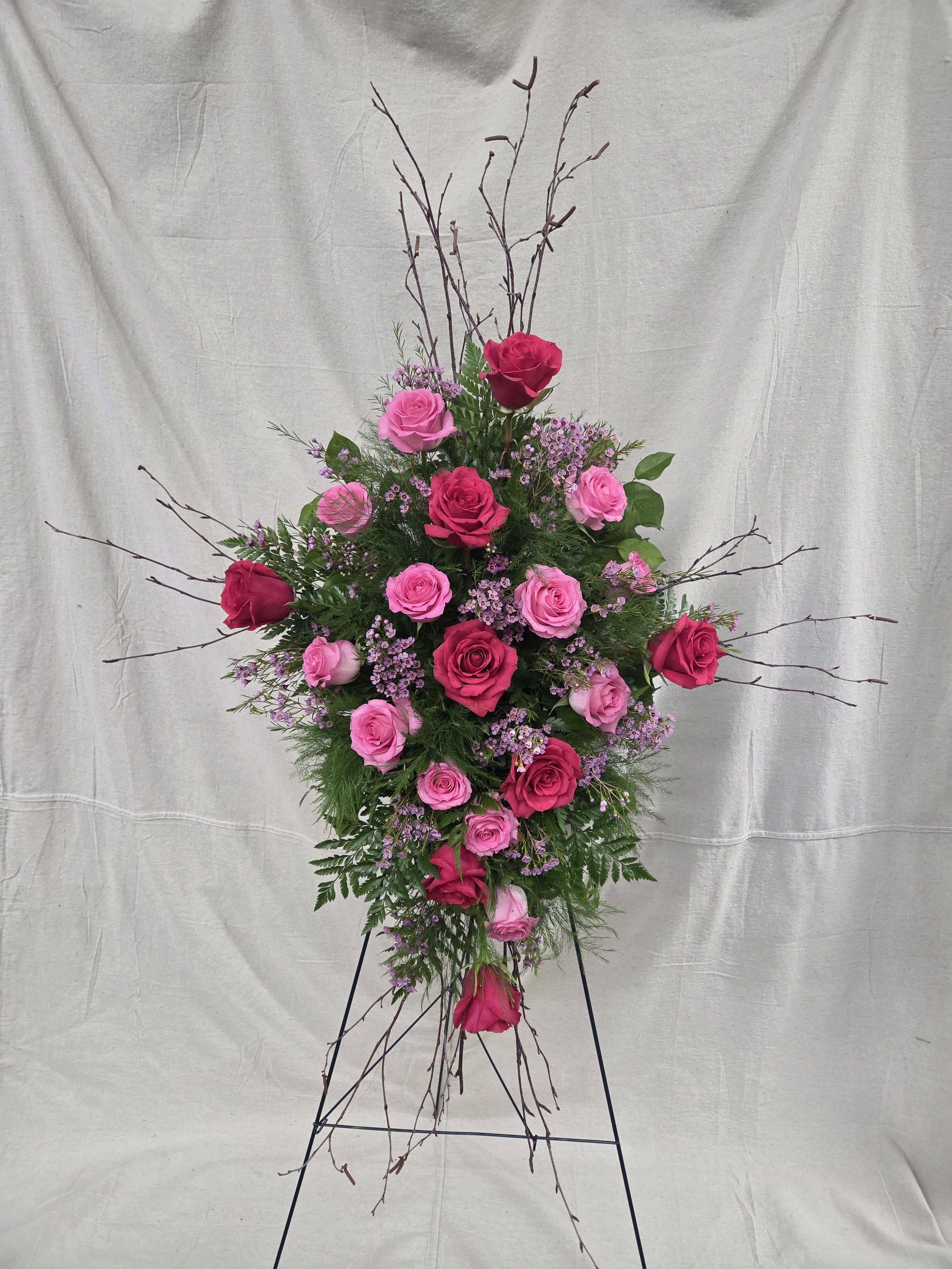 Tall standing spray of hot pink and light pink roses on a metal easel