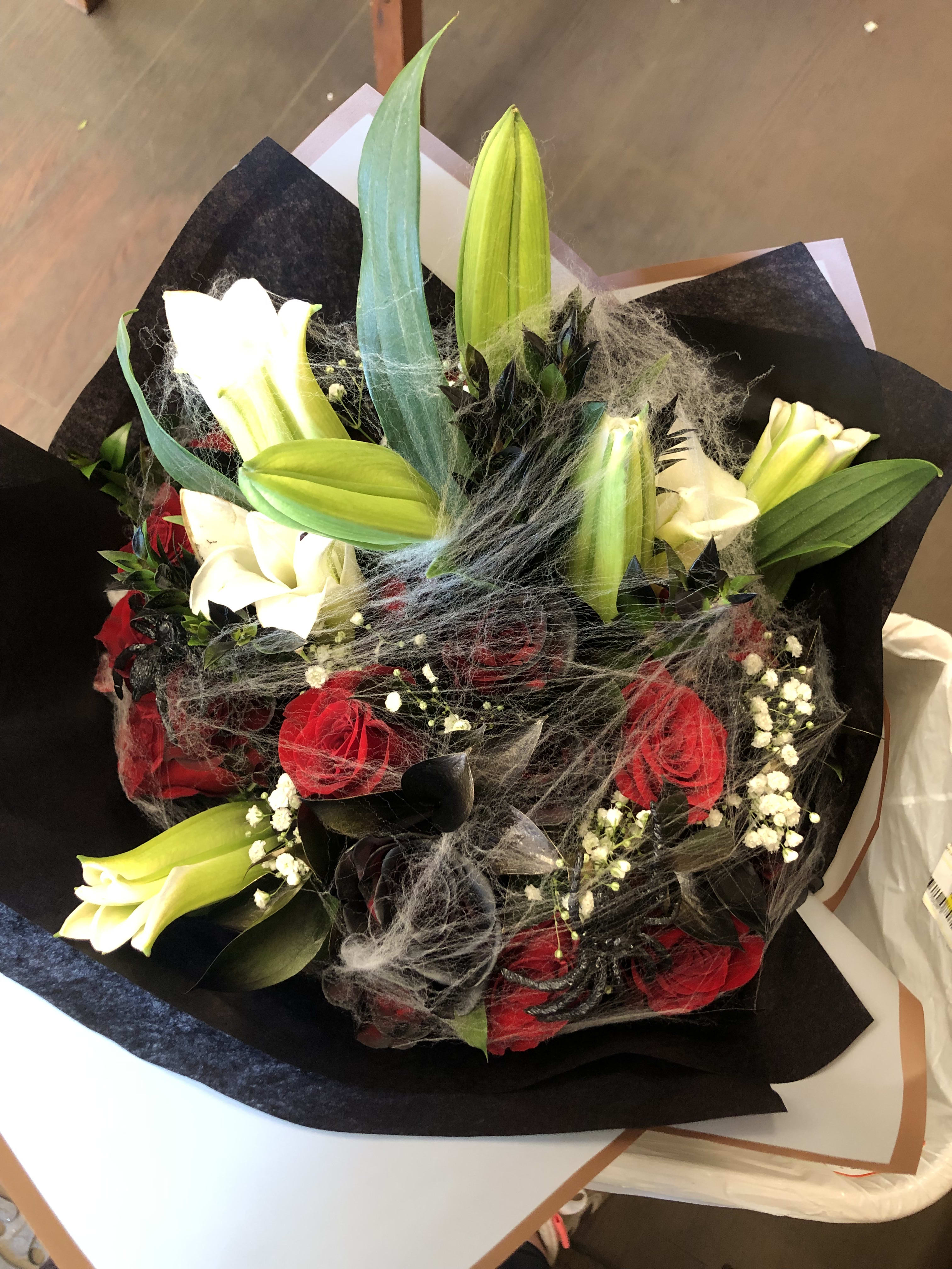 Bouquet of red roses and white lilies wrapped in black paper