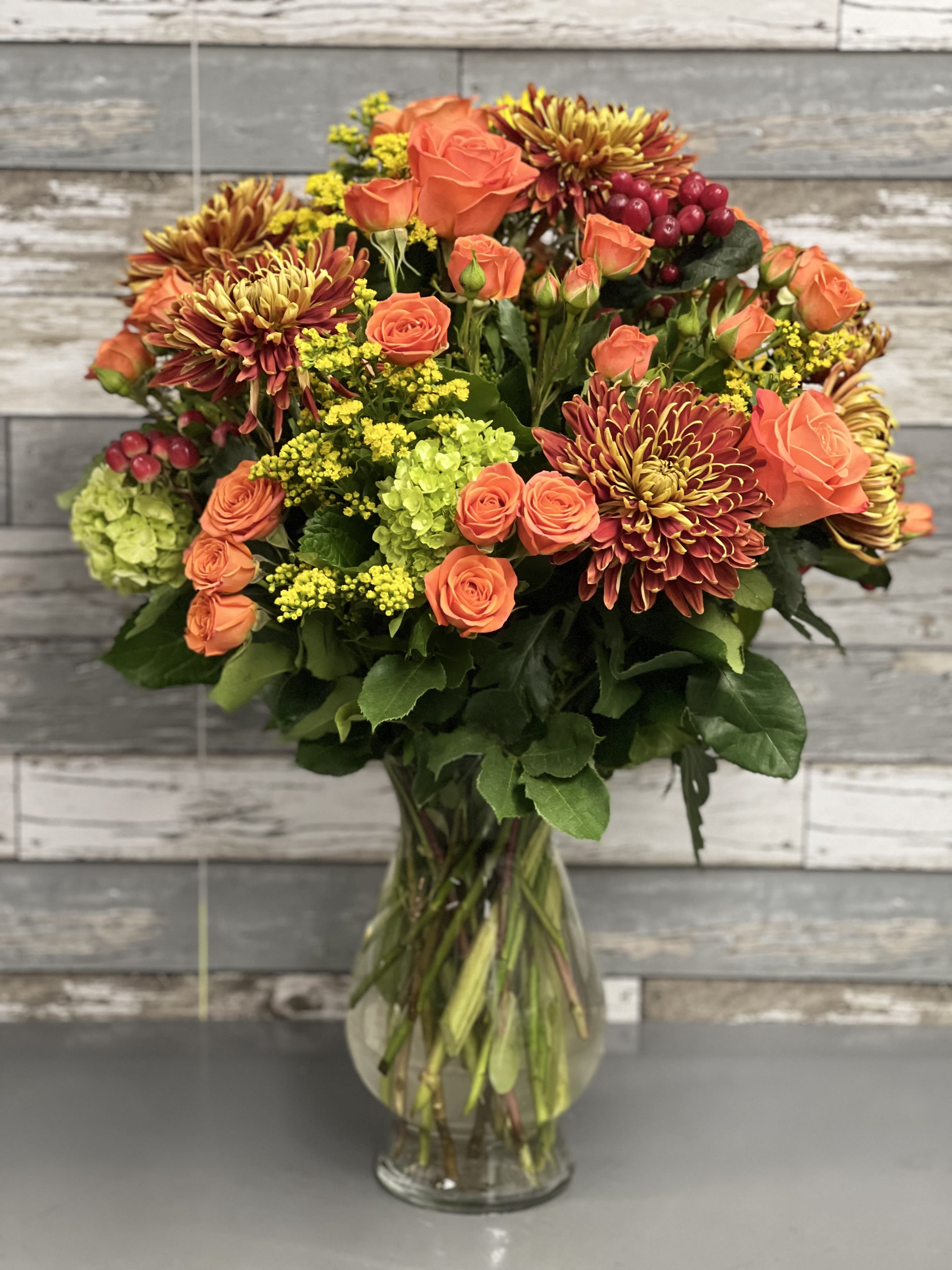 Orange roses and chrysanthemums in a clear glass vase