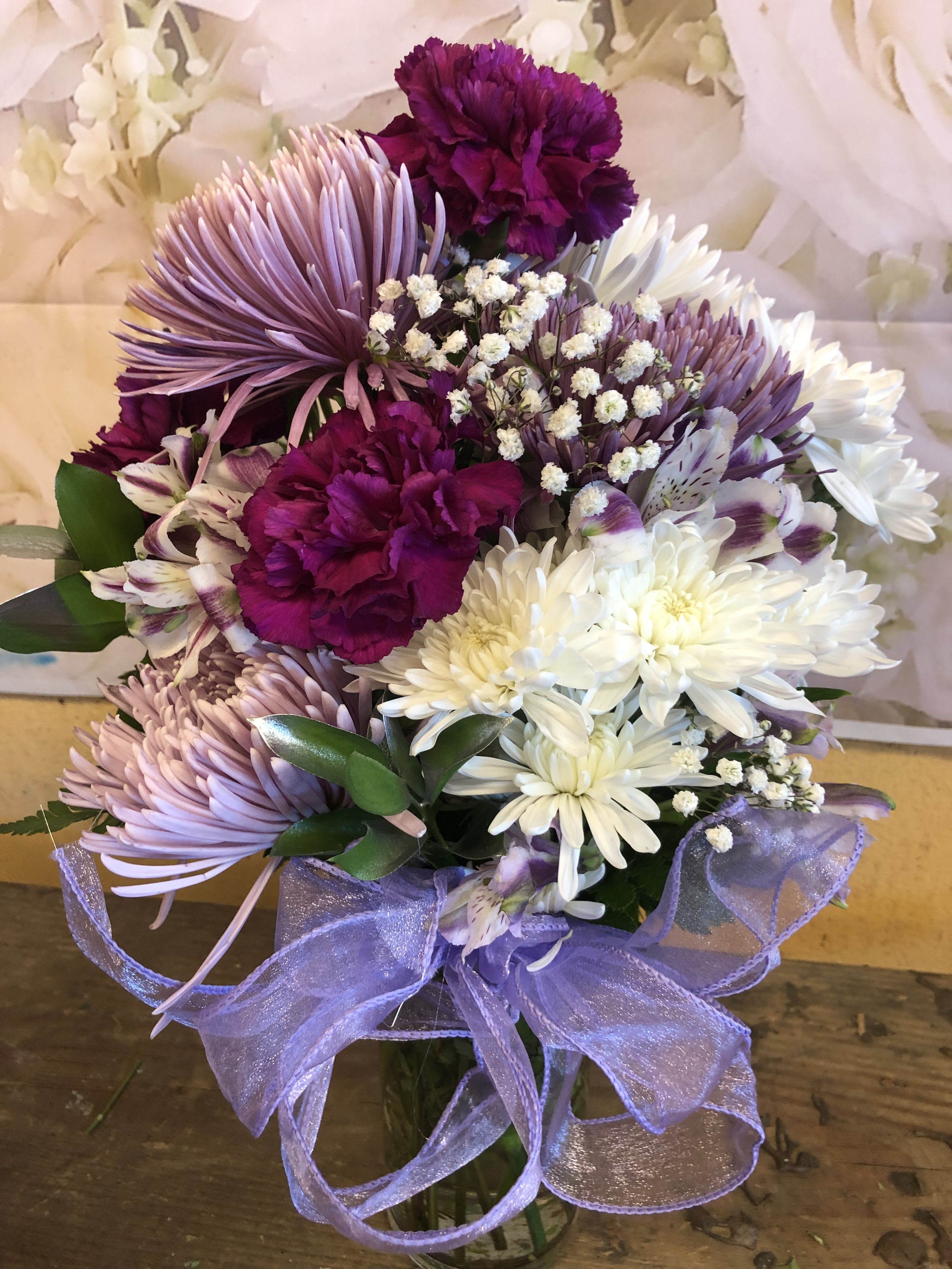 Purple and white bouquet with daisies, carnations, and alstroemeria tied with a lavender ribbon