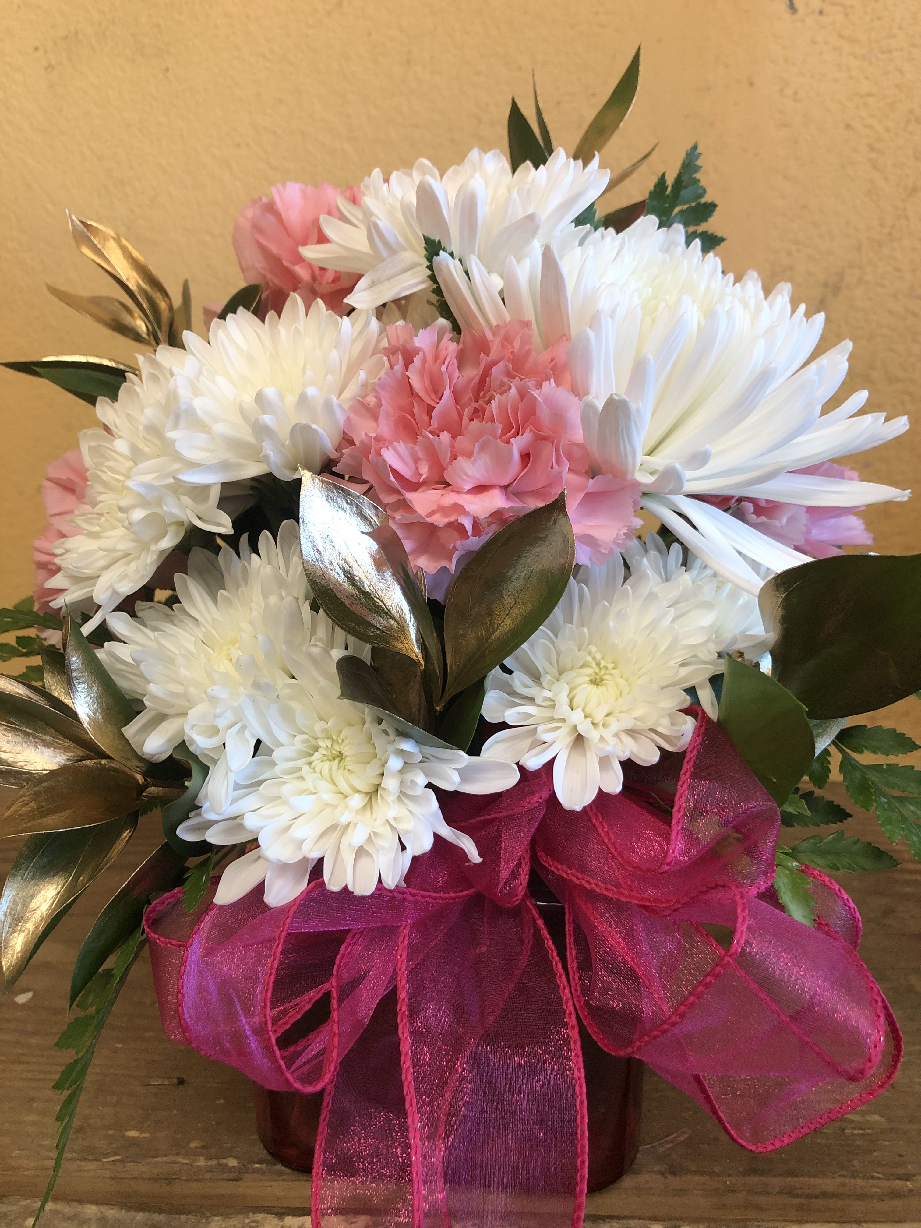 Pink and white chrysanthemum bouquet with a bright ribbon in a vase