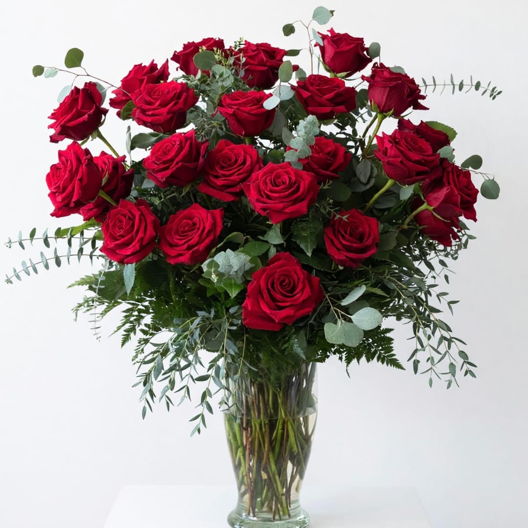 Red roses arranged in a clear glass vase with airy greenery