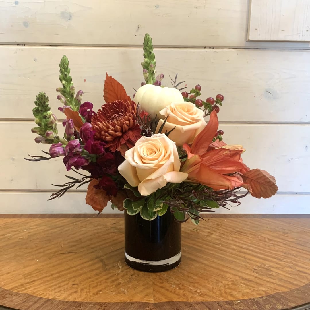 Peach roses and burgundy flowers arranged in a black vase