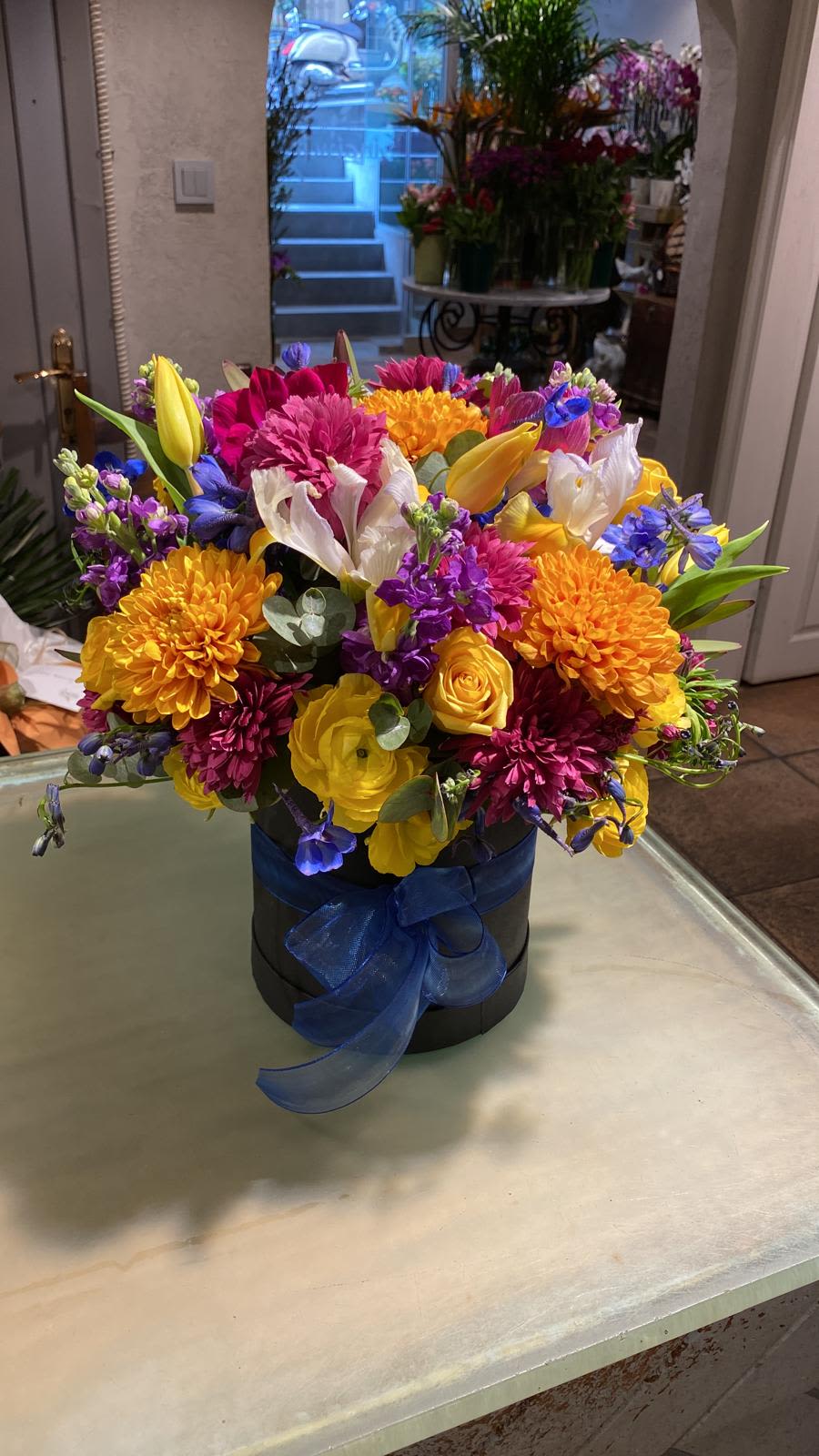 Colorful mixed bouquet in a black hatbox with a blue ribbon