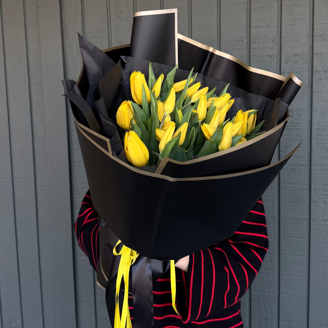 Yellow tulip bouquet wrapped in black paper with gold trim