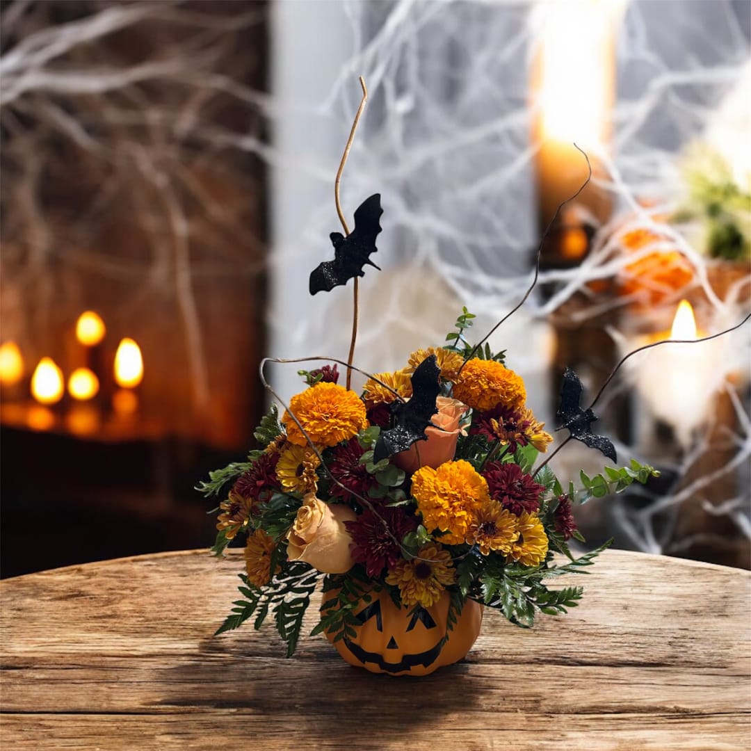 Halloween flower arrangement in a jack-o'-lantern container with bat picks
