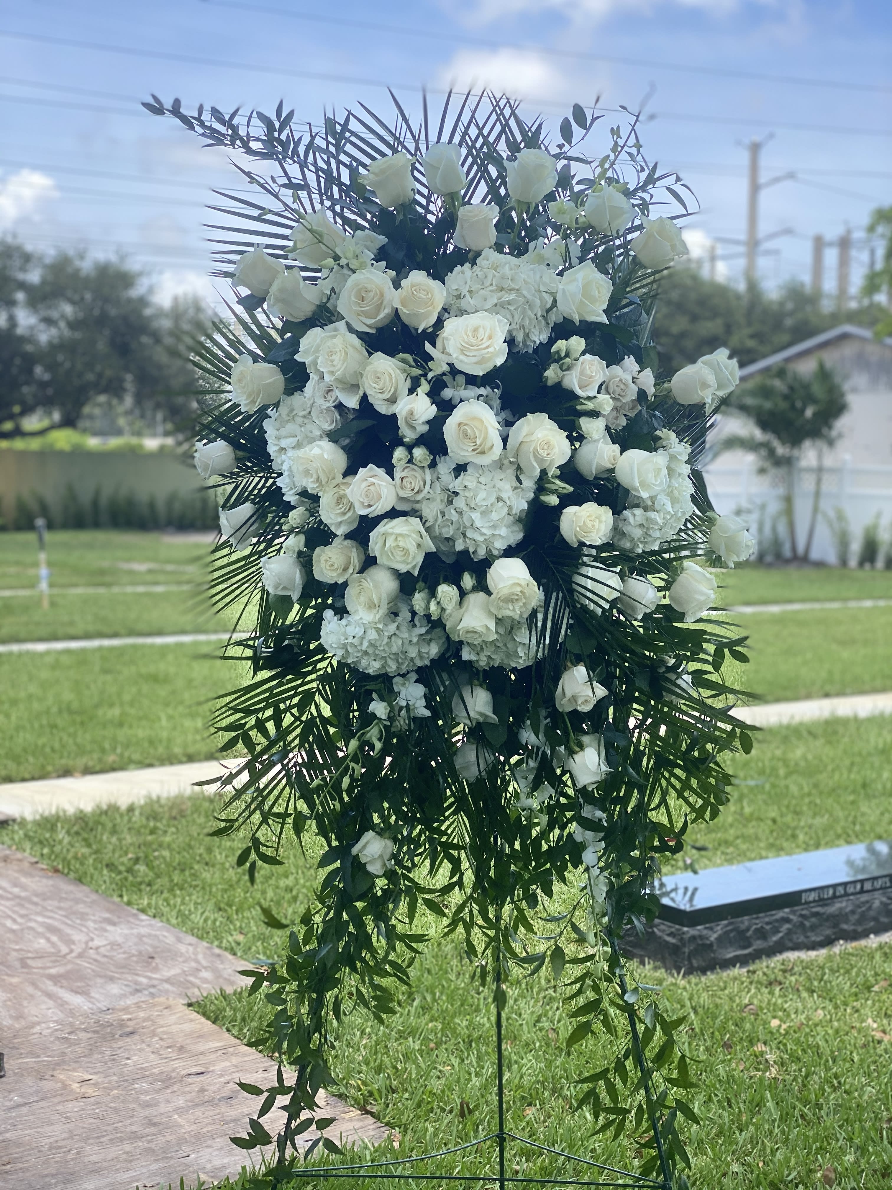 Large white floral standing spray with roses and cascading greenery
