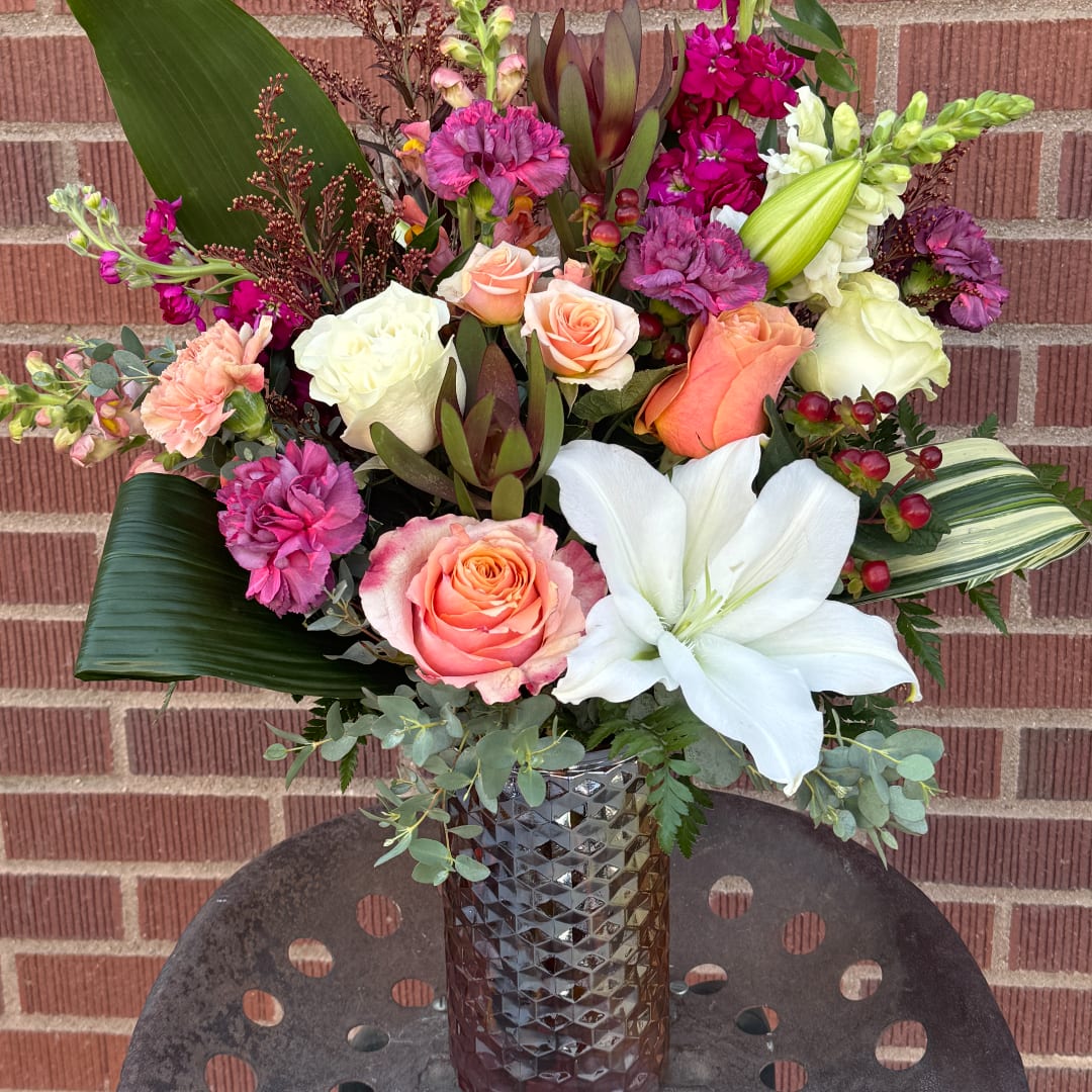Mixed bouquet in a textured vase with roses, lilies, and carnations