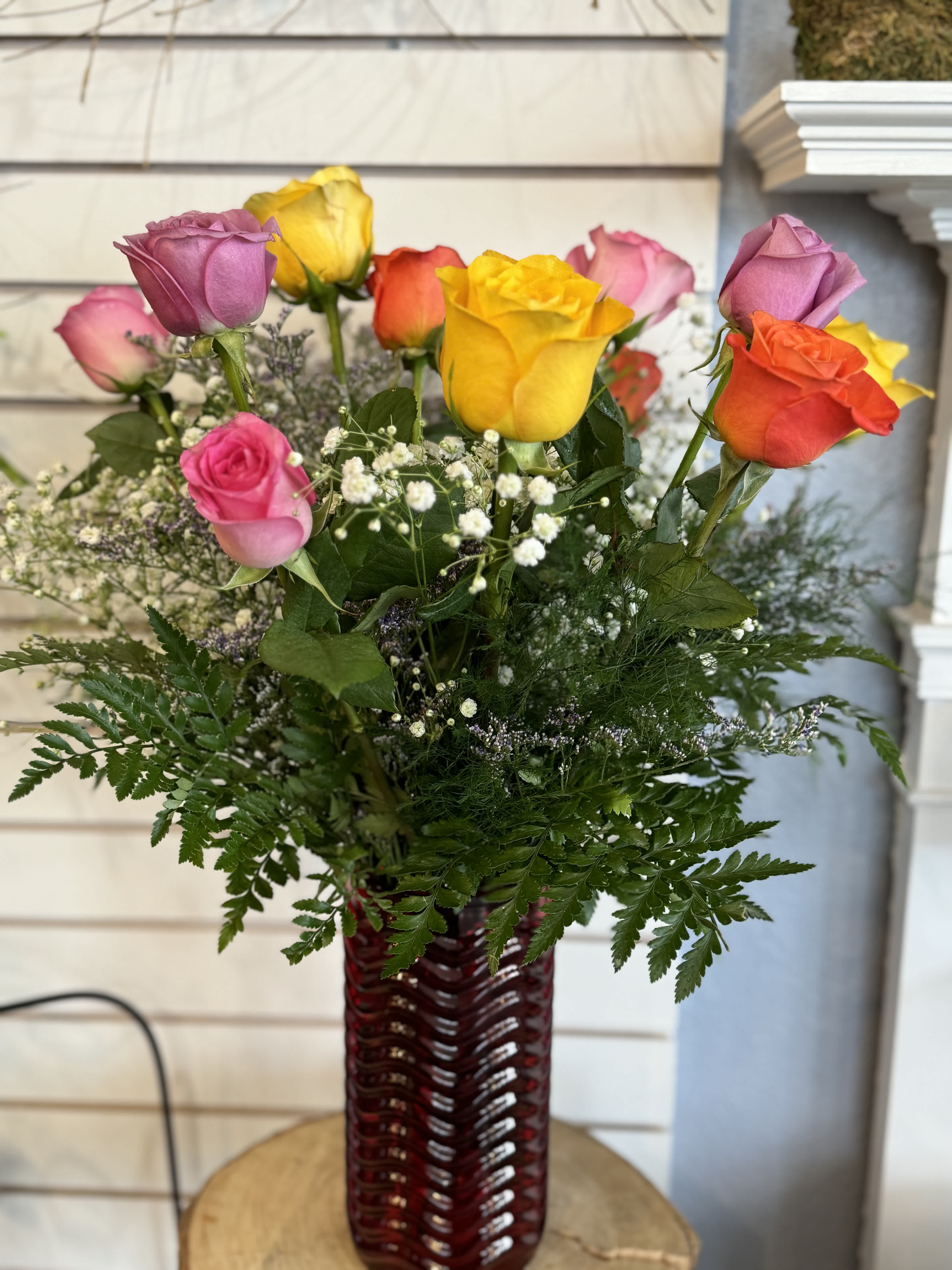 Mixed roses in a red glass vase with baby's breath