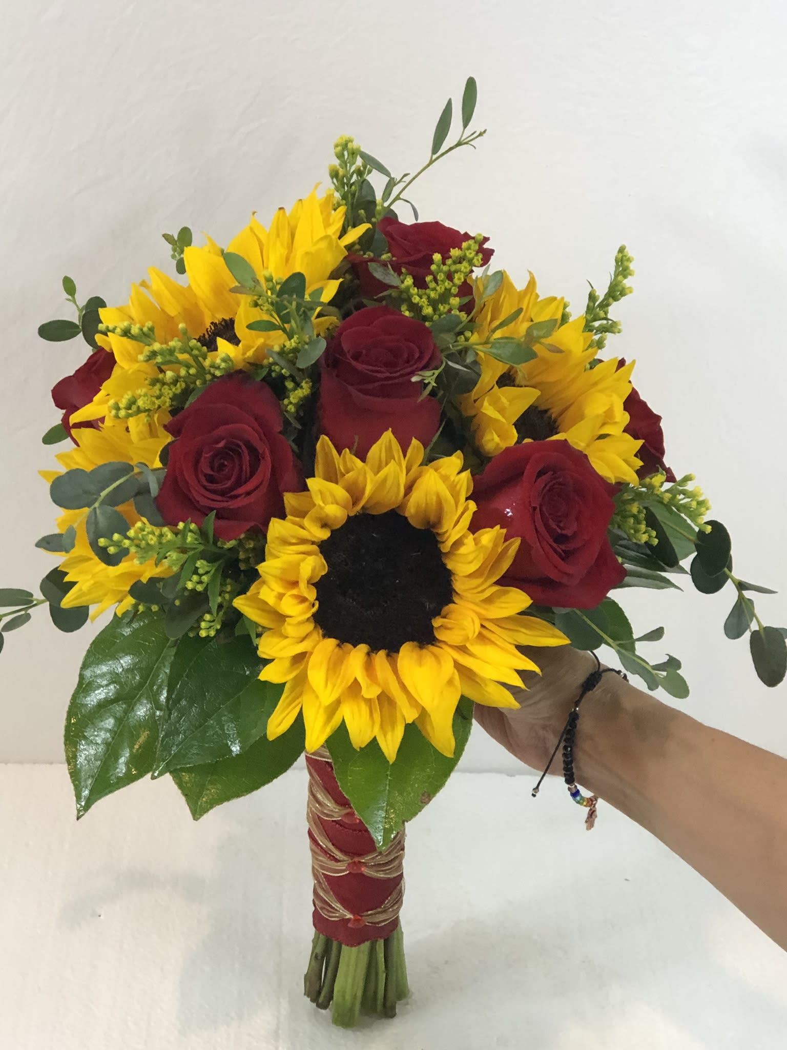 Bouquet of red roses and yellow sunflowers with greenery