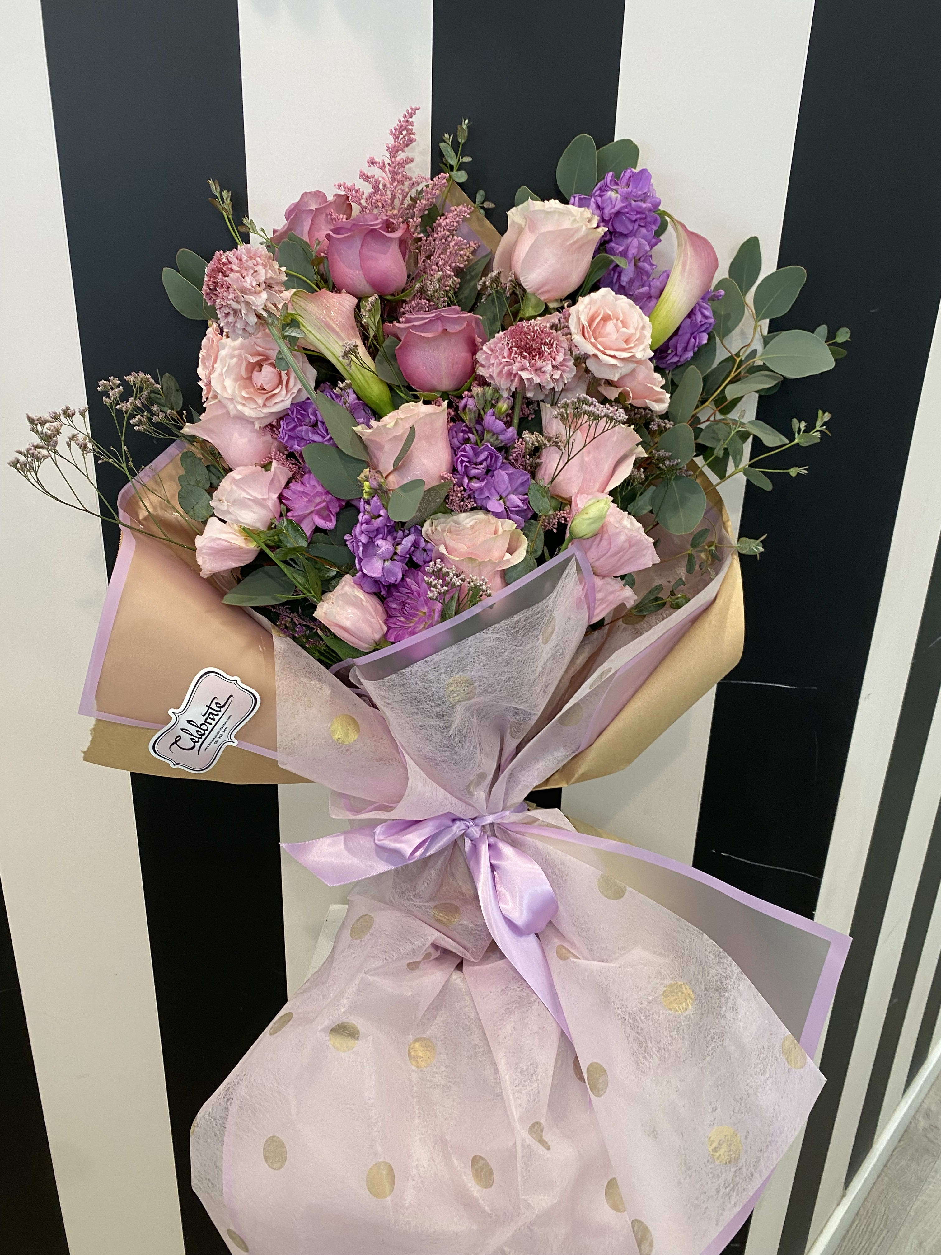 Bouquet of pink and purple flowers wrapped in pastel paper with a ribbon