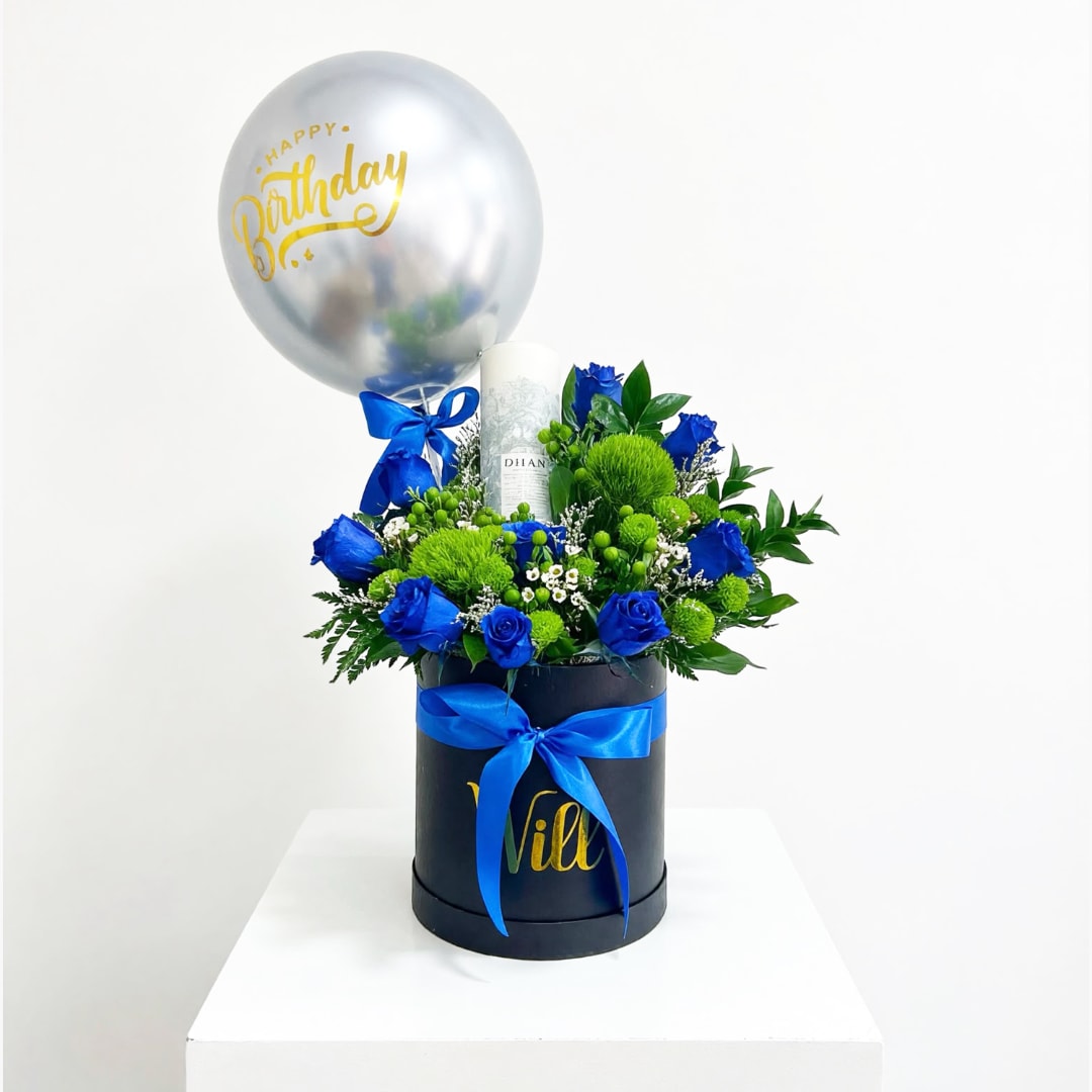 Blue roses and green pompons in a black hatbox with a birthday balloon
